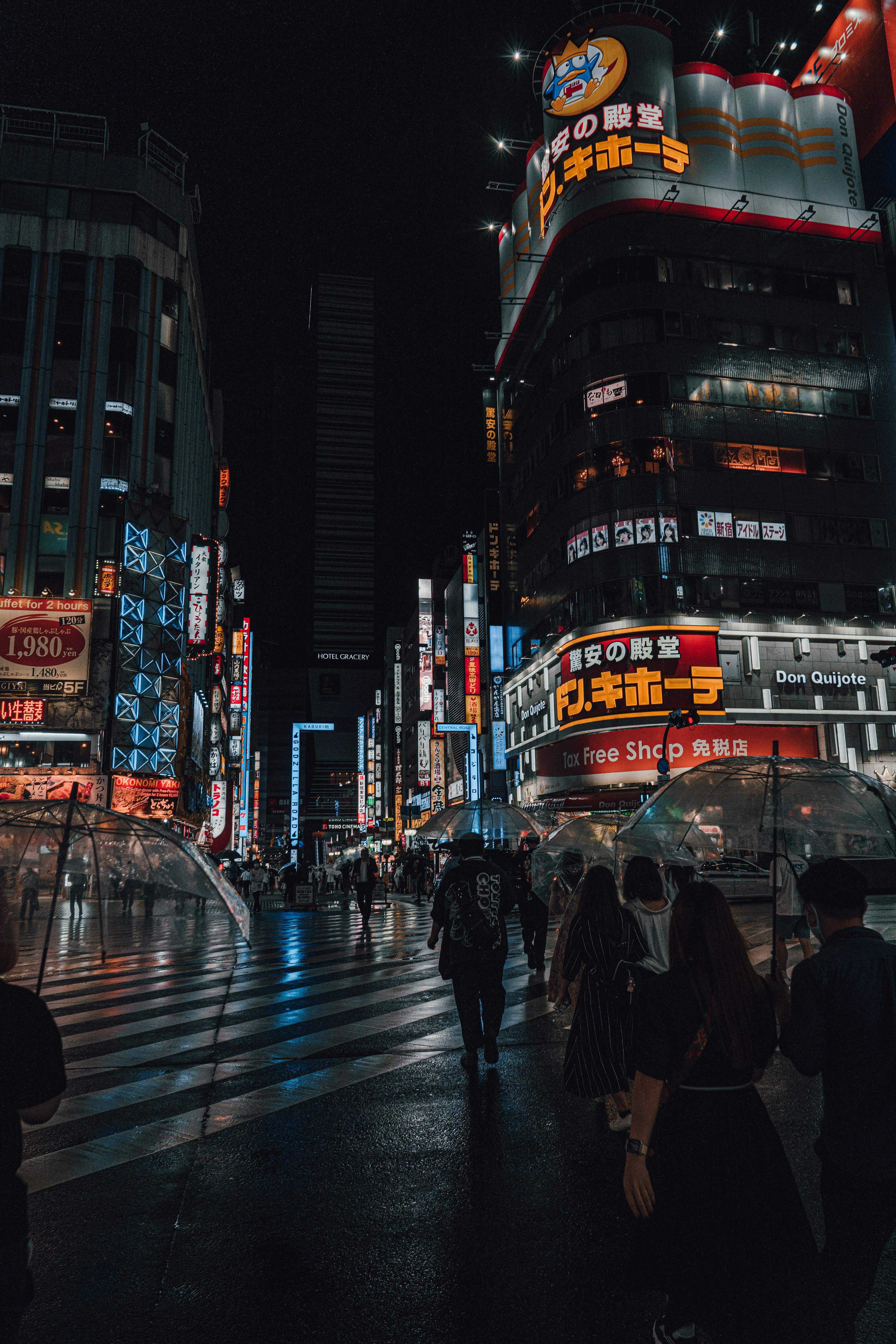 Nighttime city street corner with people and bright neon signs