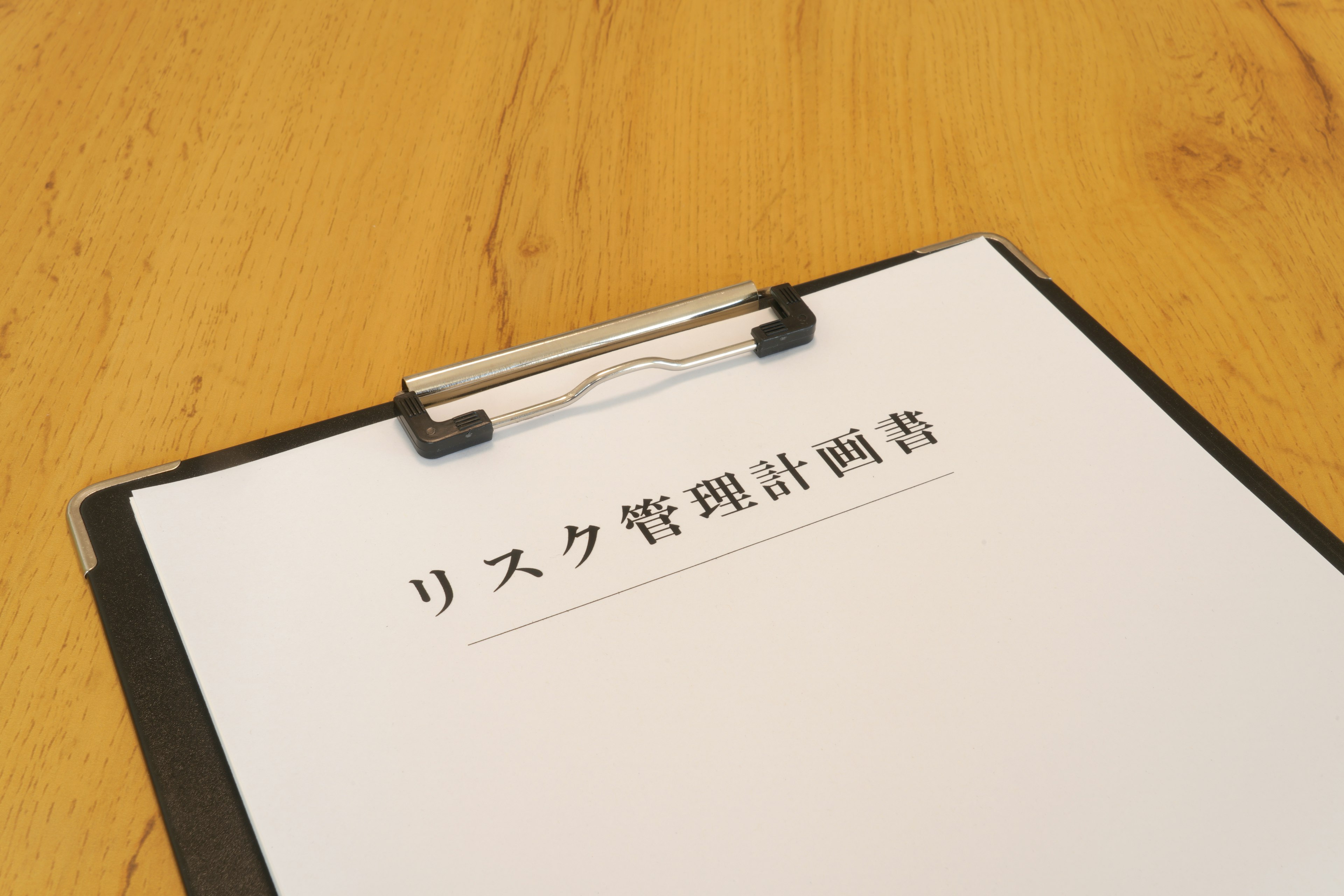 A white paper on a clipboard with risk management plan written in Japanese