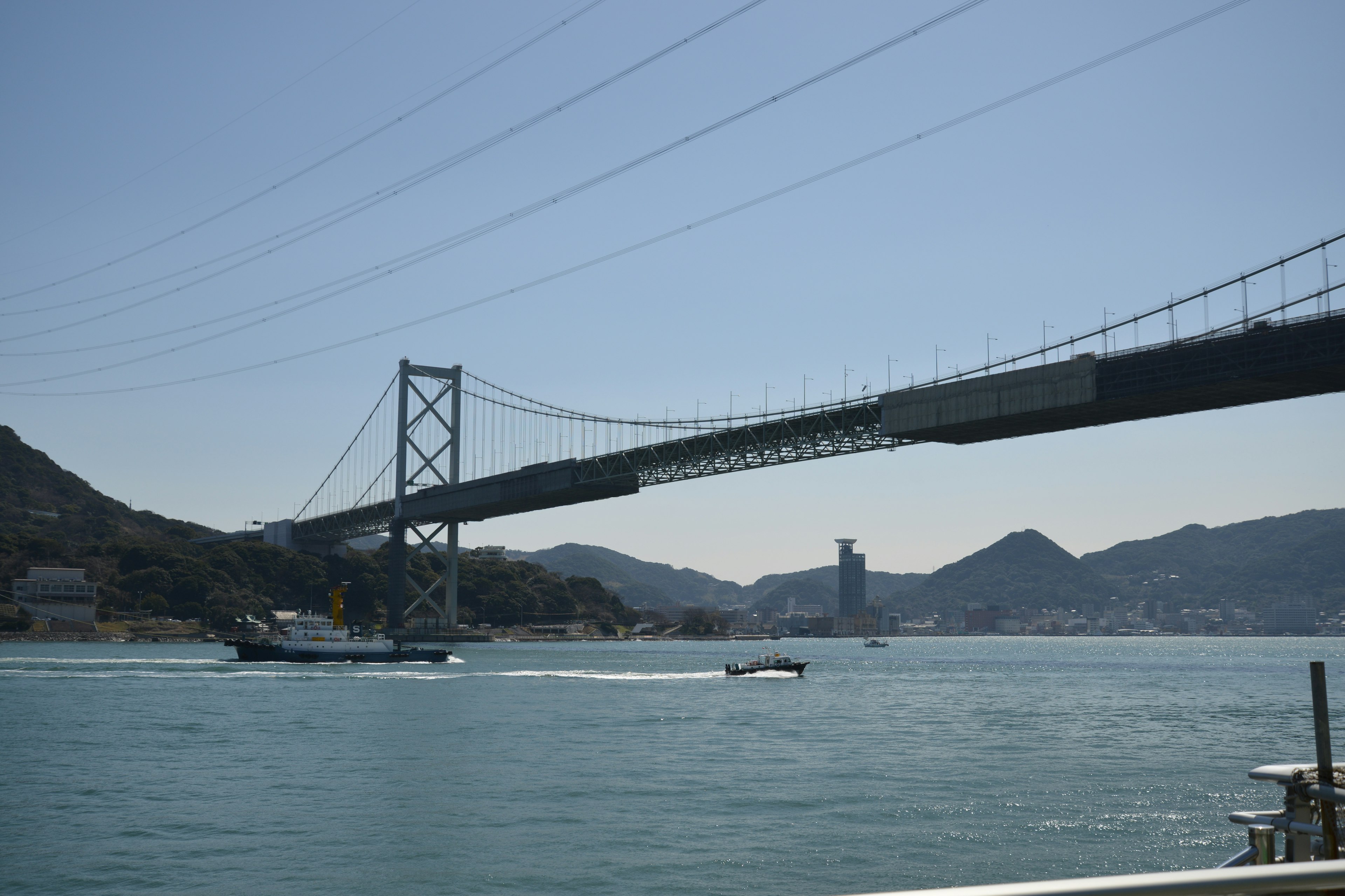 Vue du pont Akashi Kaikyō avec un bateau passant dans l'eau