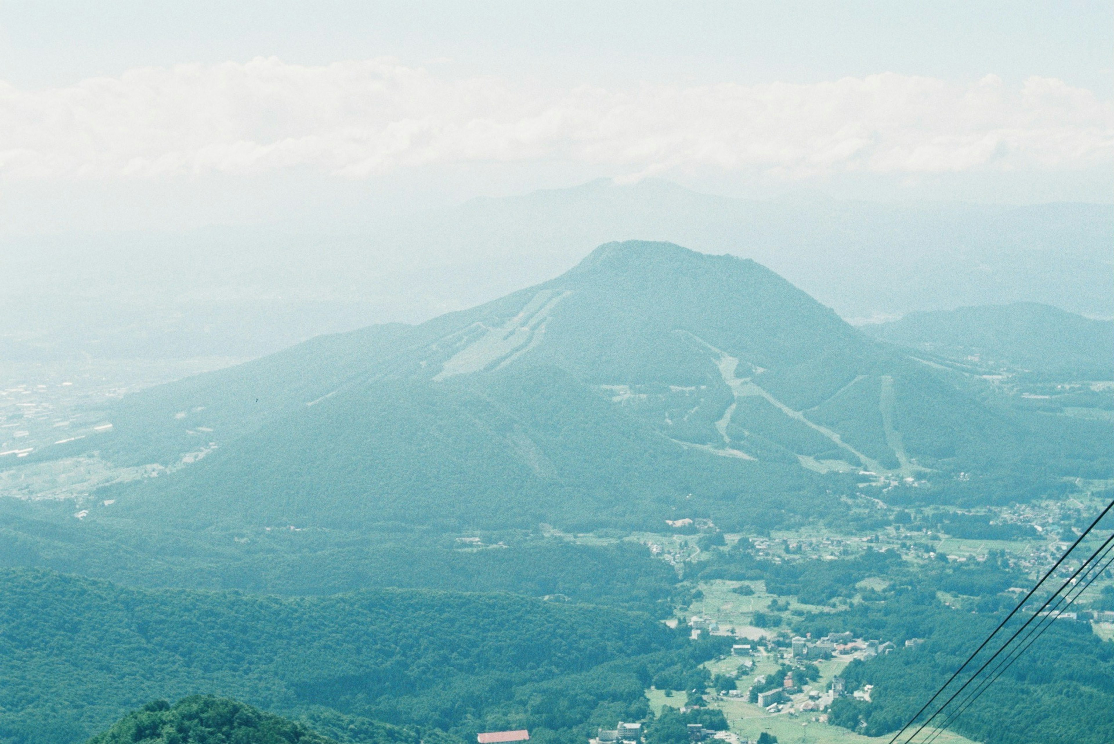 青い山と谷の風景、遠くに雪をかぶった山が見える