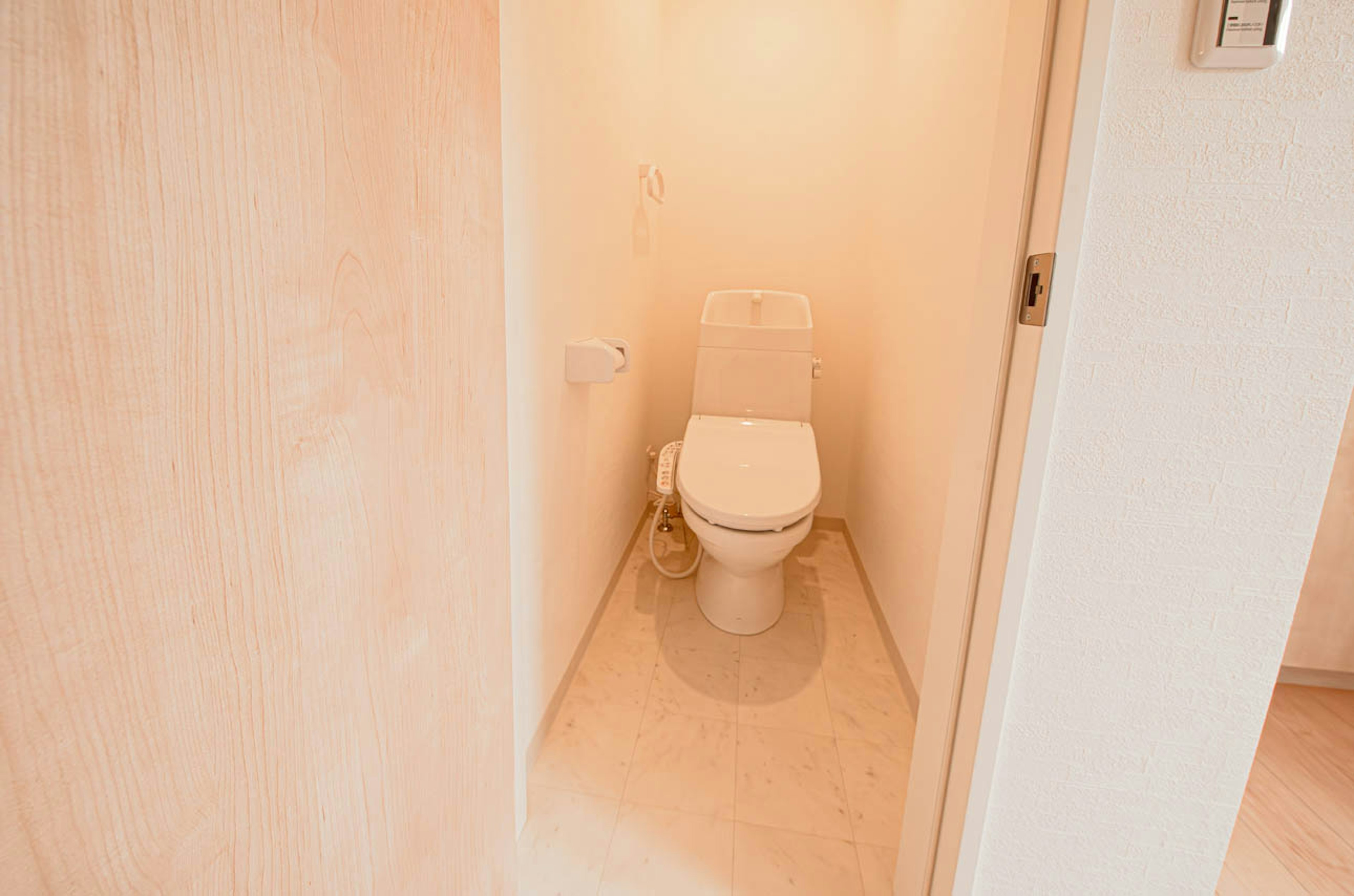 Image d'une salle de bain lumineuse avec un mur et un sol blancs présentant des toilettes