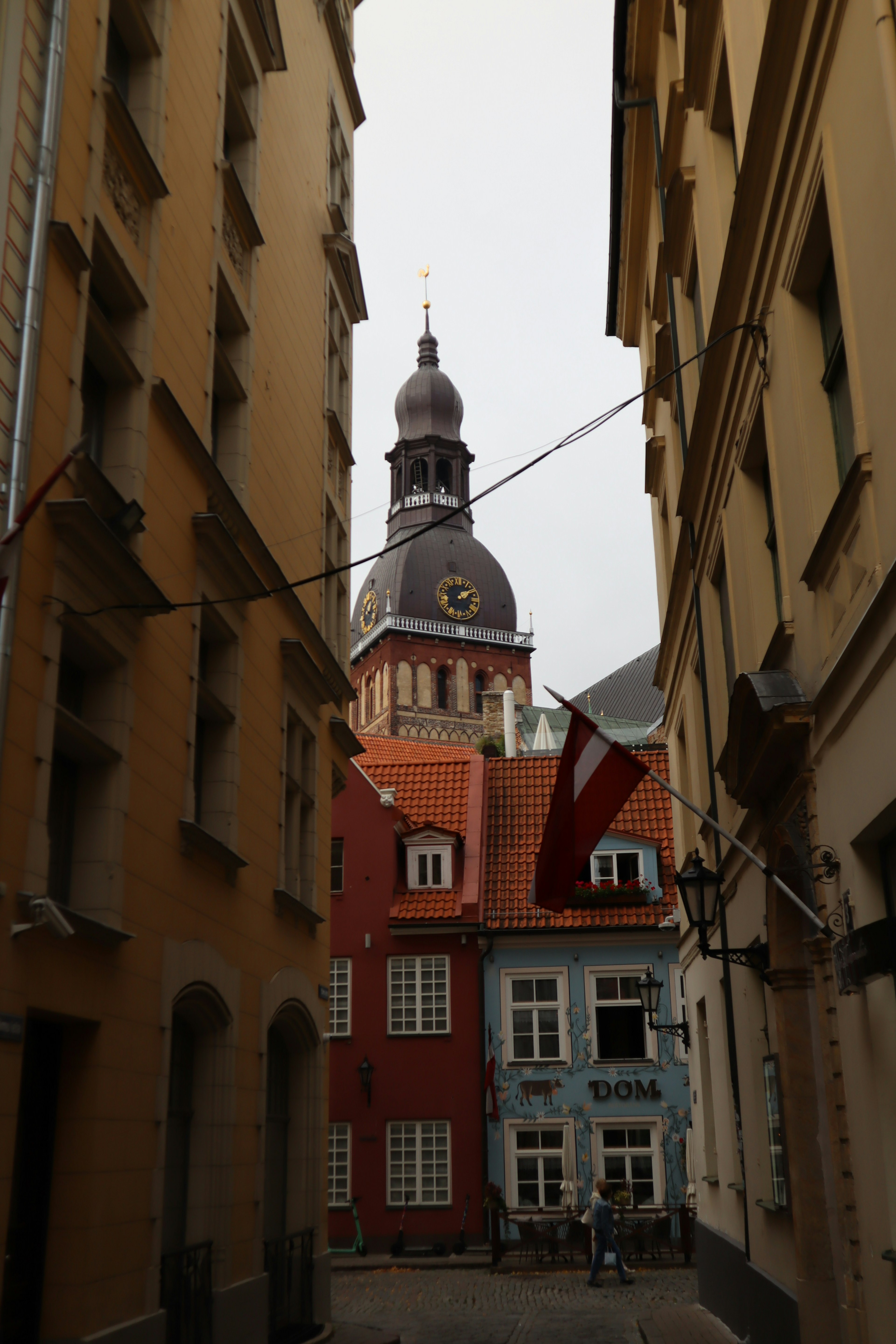 Enge Gasse gesäumt von bunten Gebäuden und einem Glockenturm