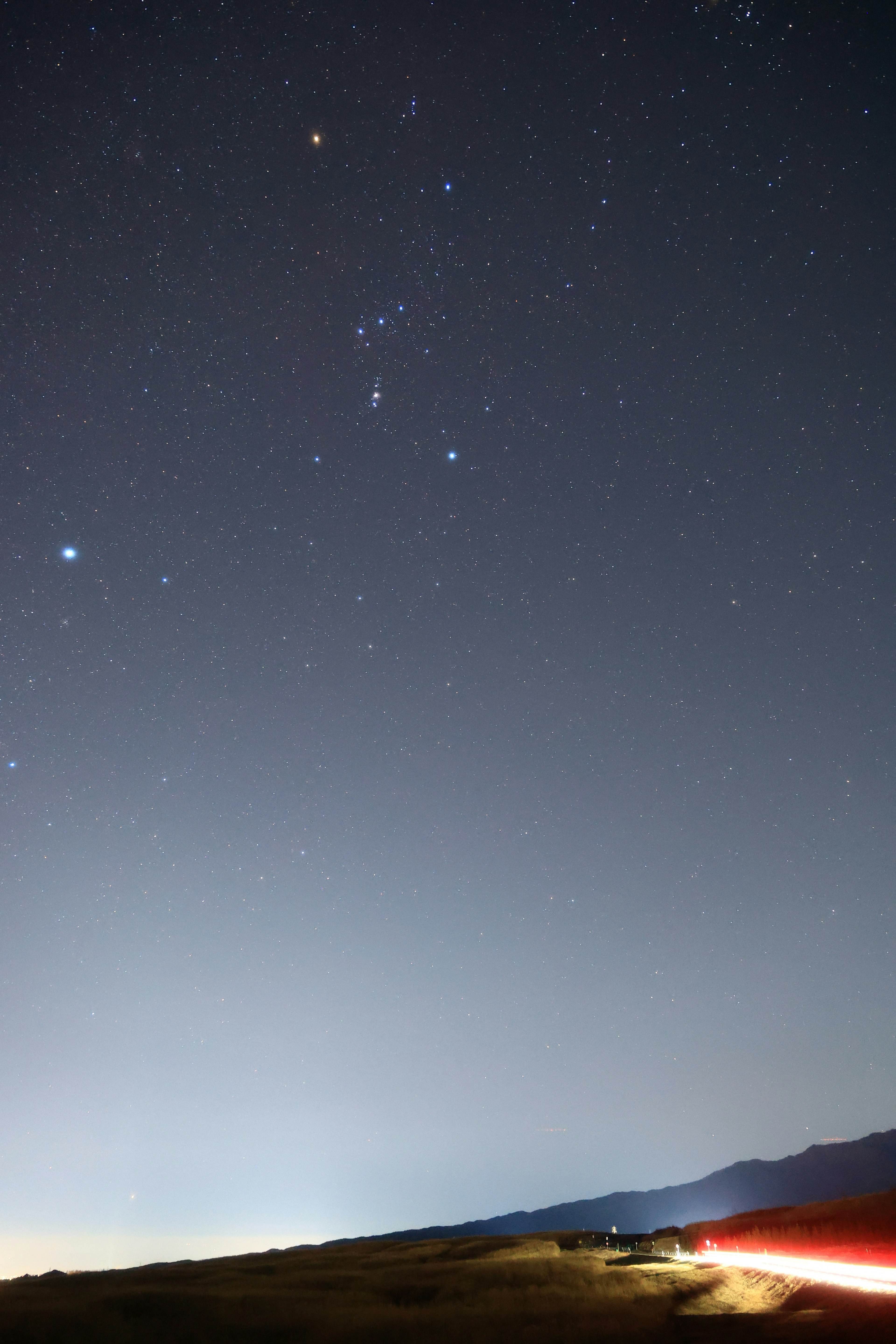 Silhouette of mountains under a starry sky with light trails