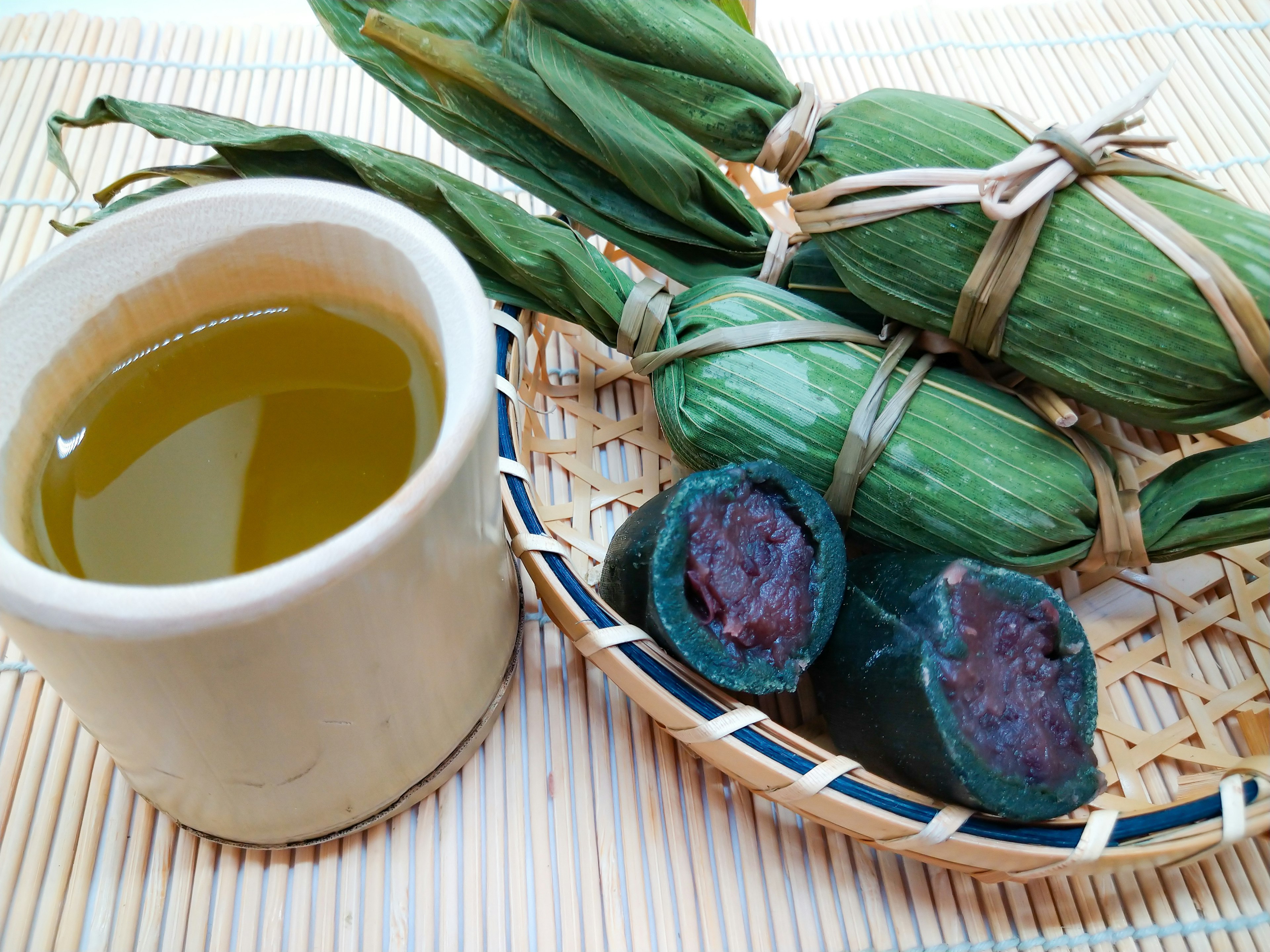 緑の葉で包まれた食べ物とお茶の入ったカップ