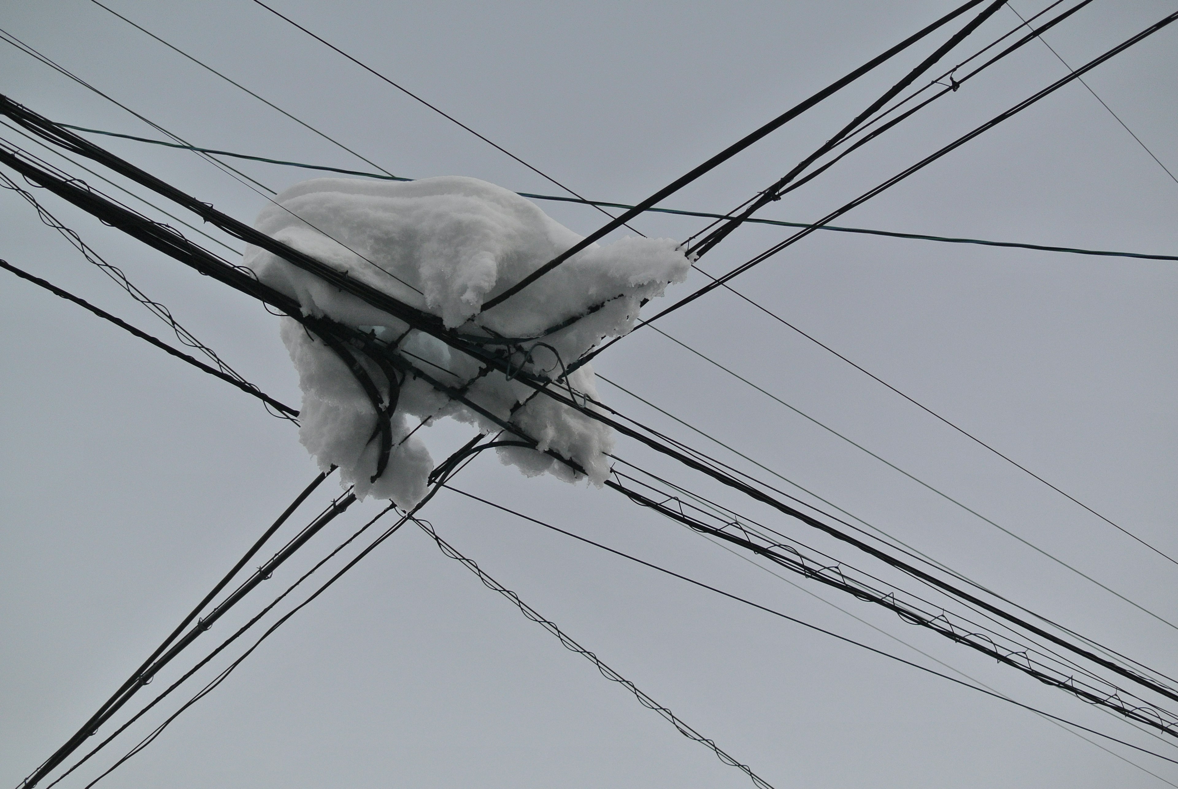 電線に積もった雪の塊と灰色の空