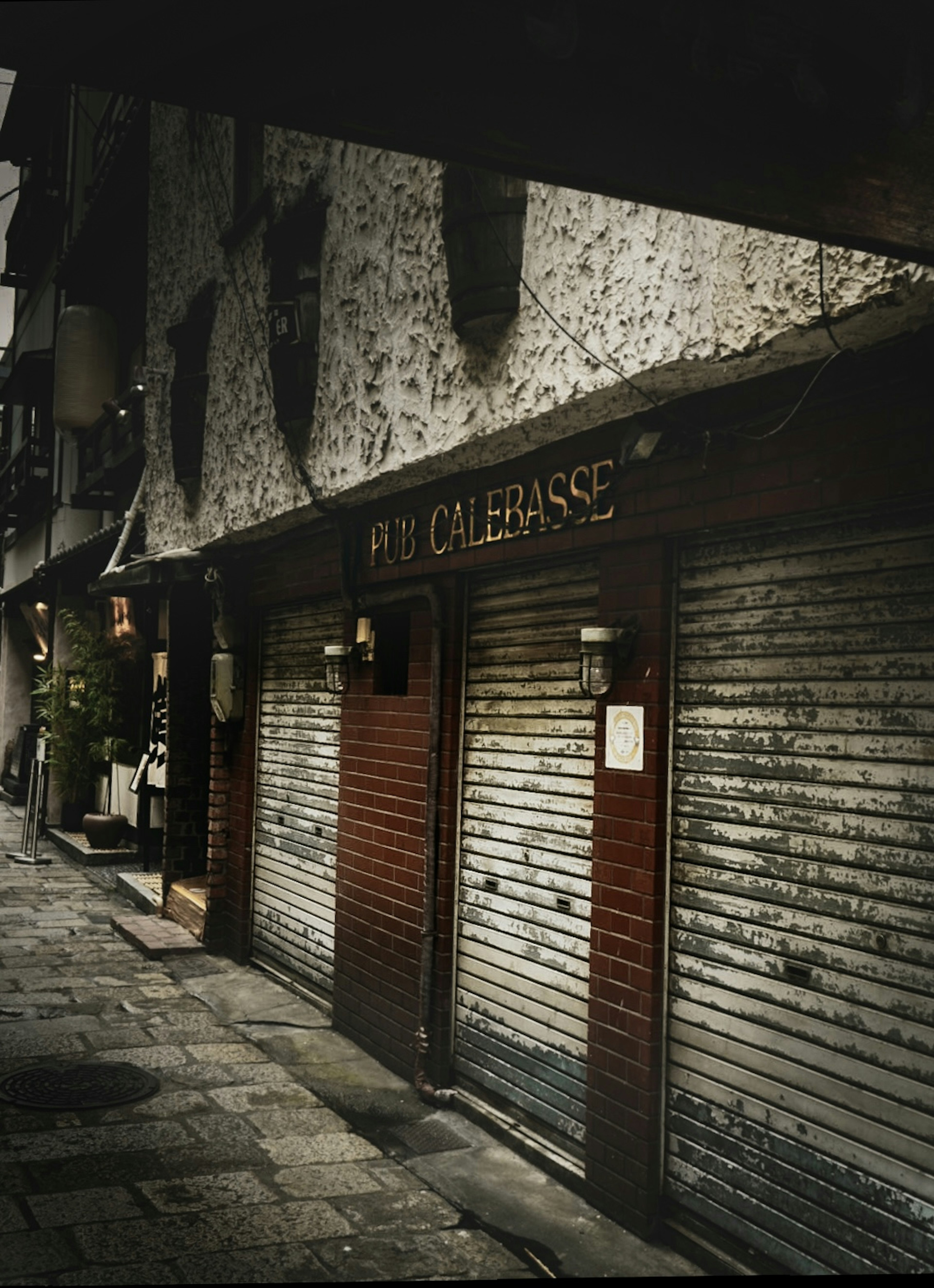 View of a street with closed shop shutters and a vintage sign