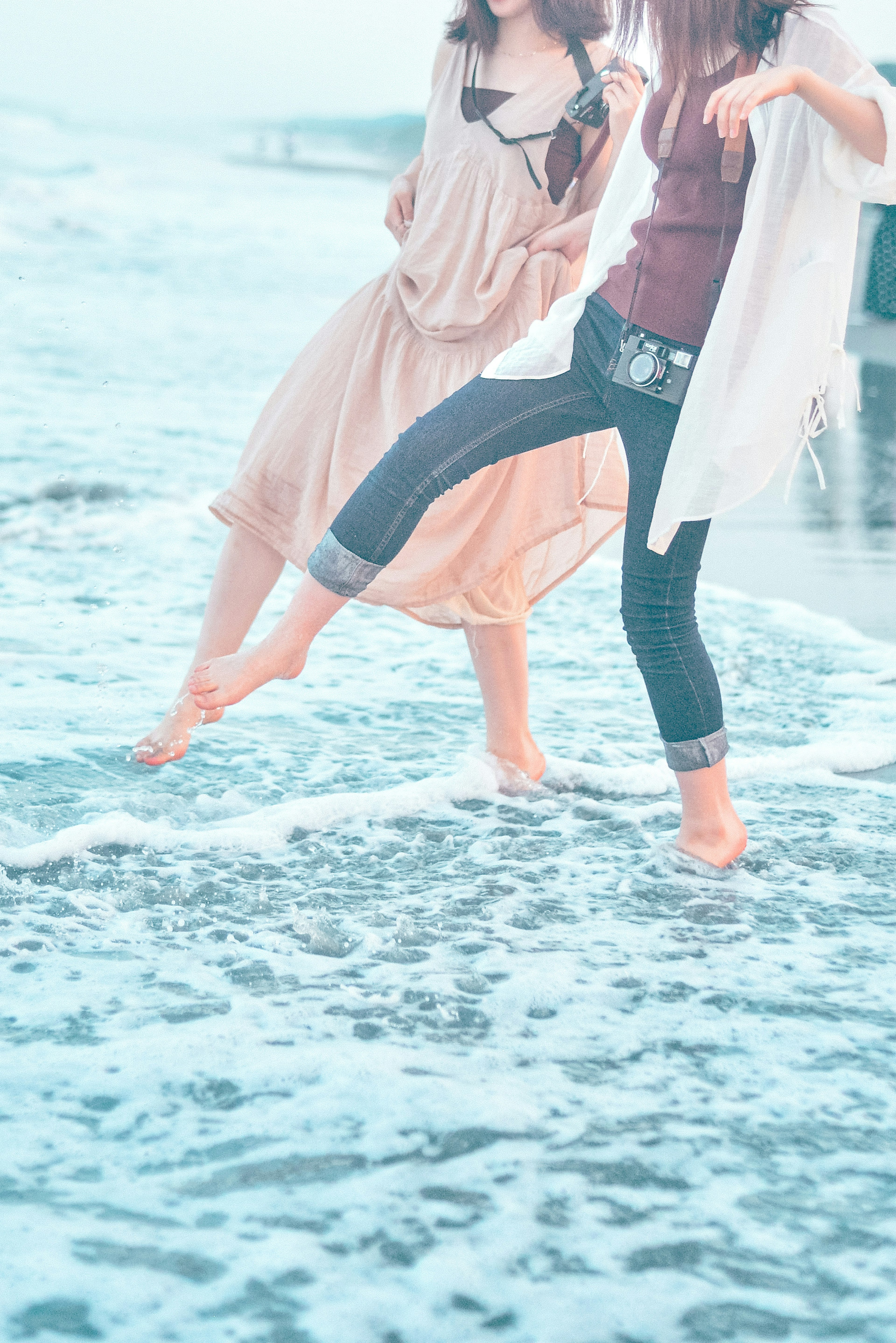 Zwei Frauen genießen den Strand, während sie durch die Wellen gehen