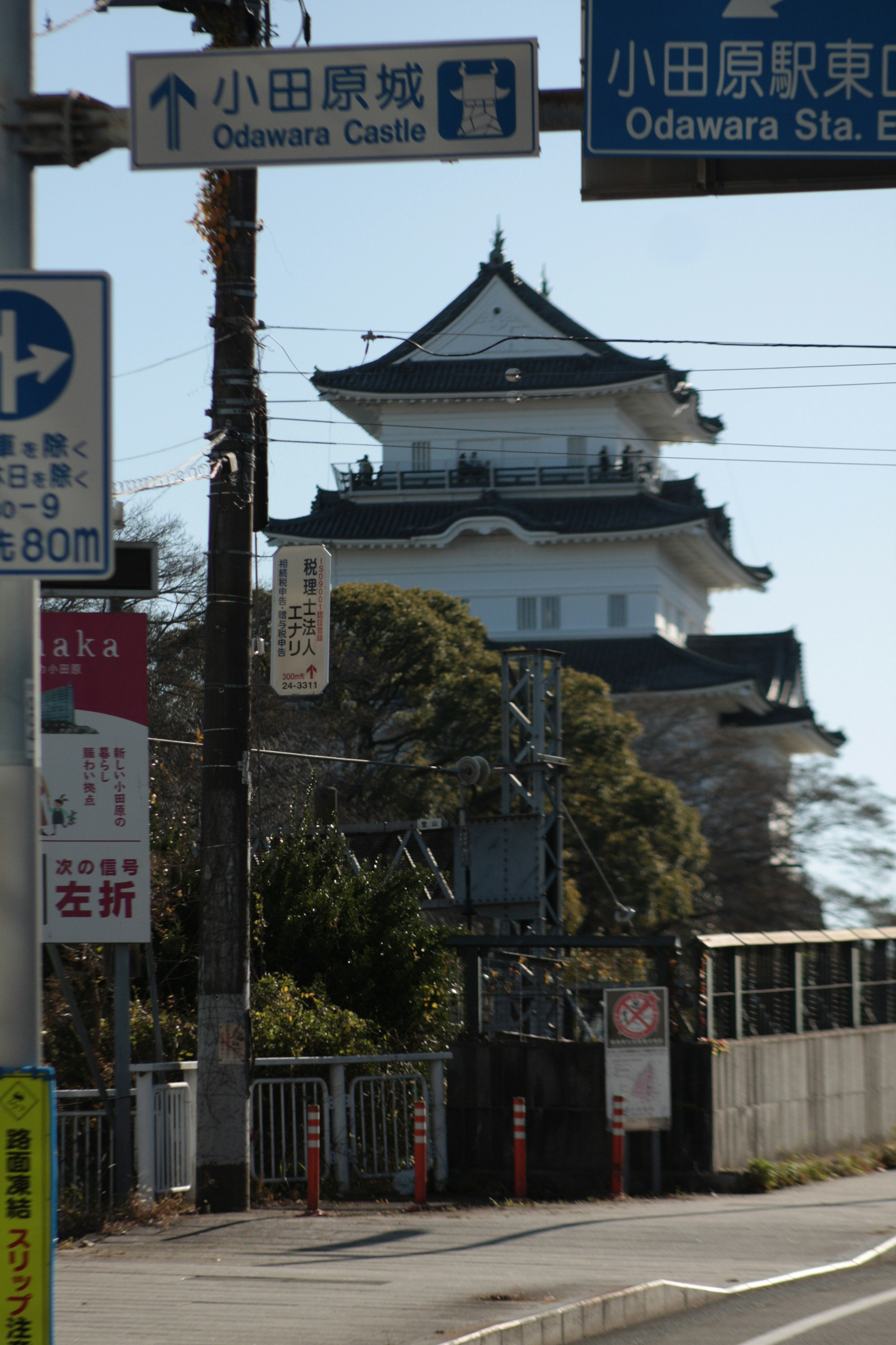 小田原城の特徴的な建物と周囲の交通標識が見える