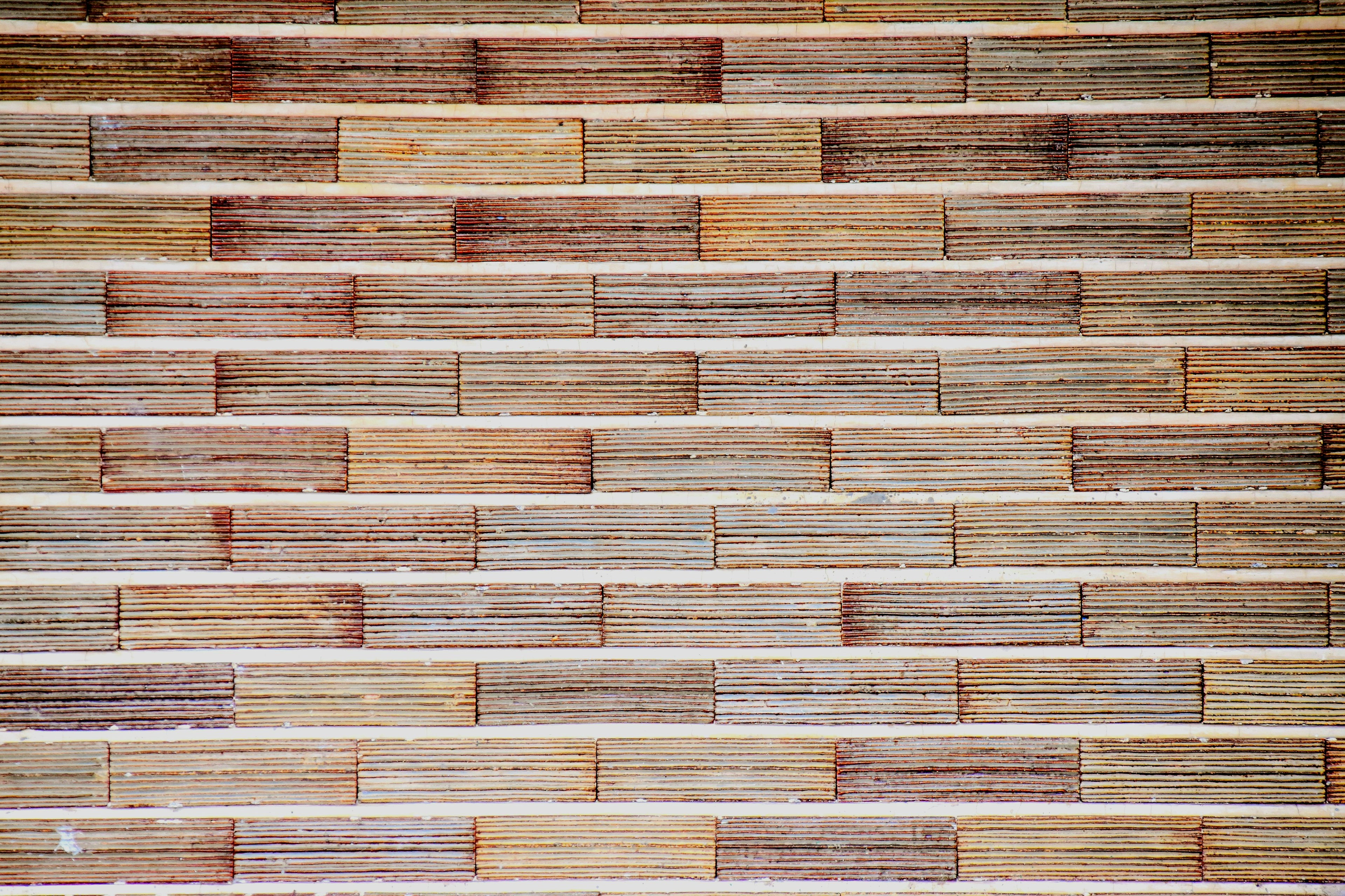 Warm-colored wall made of wooden tiles arranged in a linear pattern