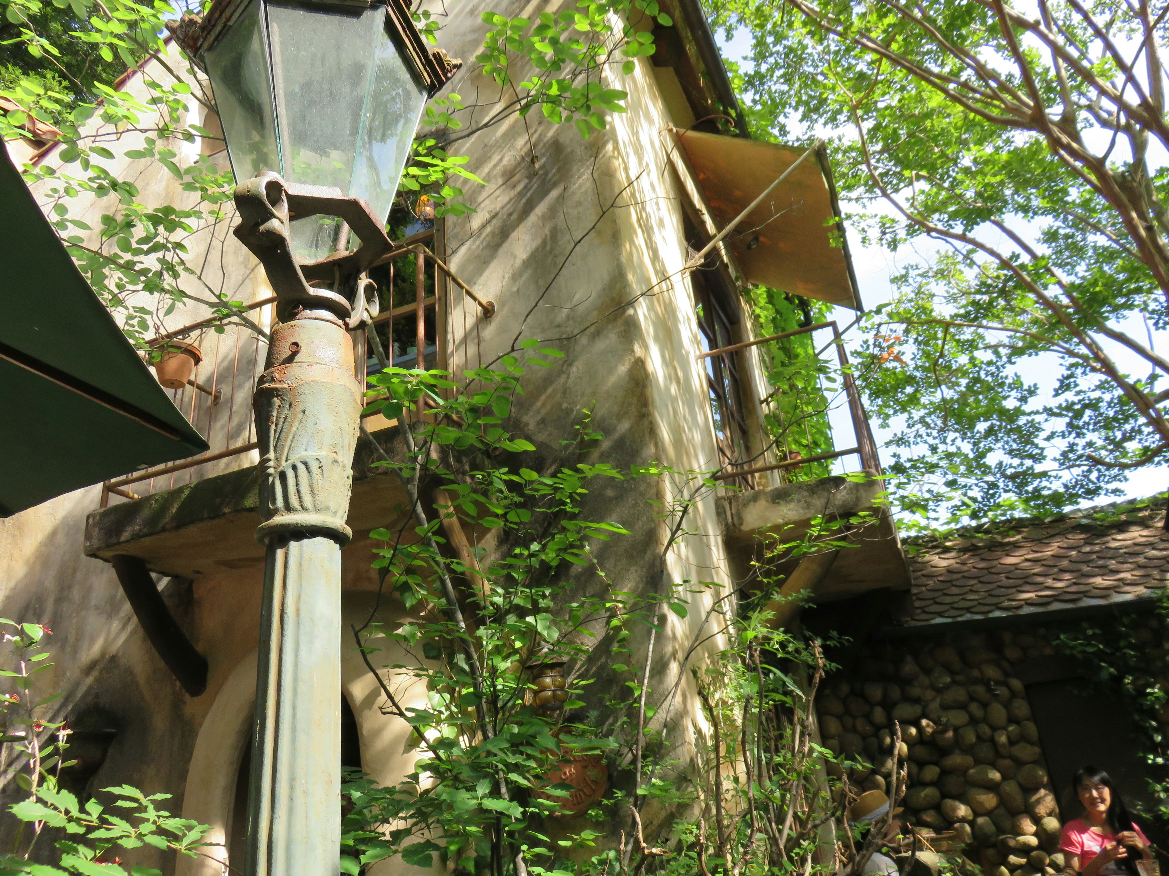 Image of an old building surrounded by greenery and a street lamp