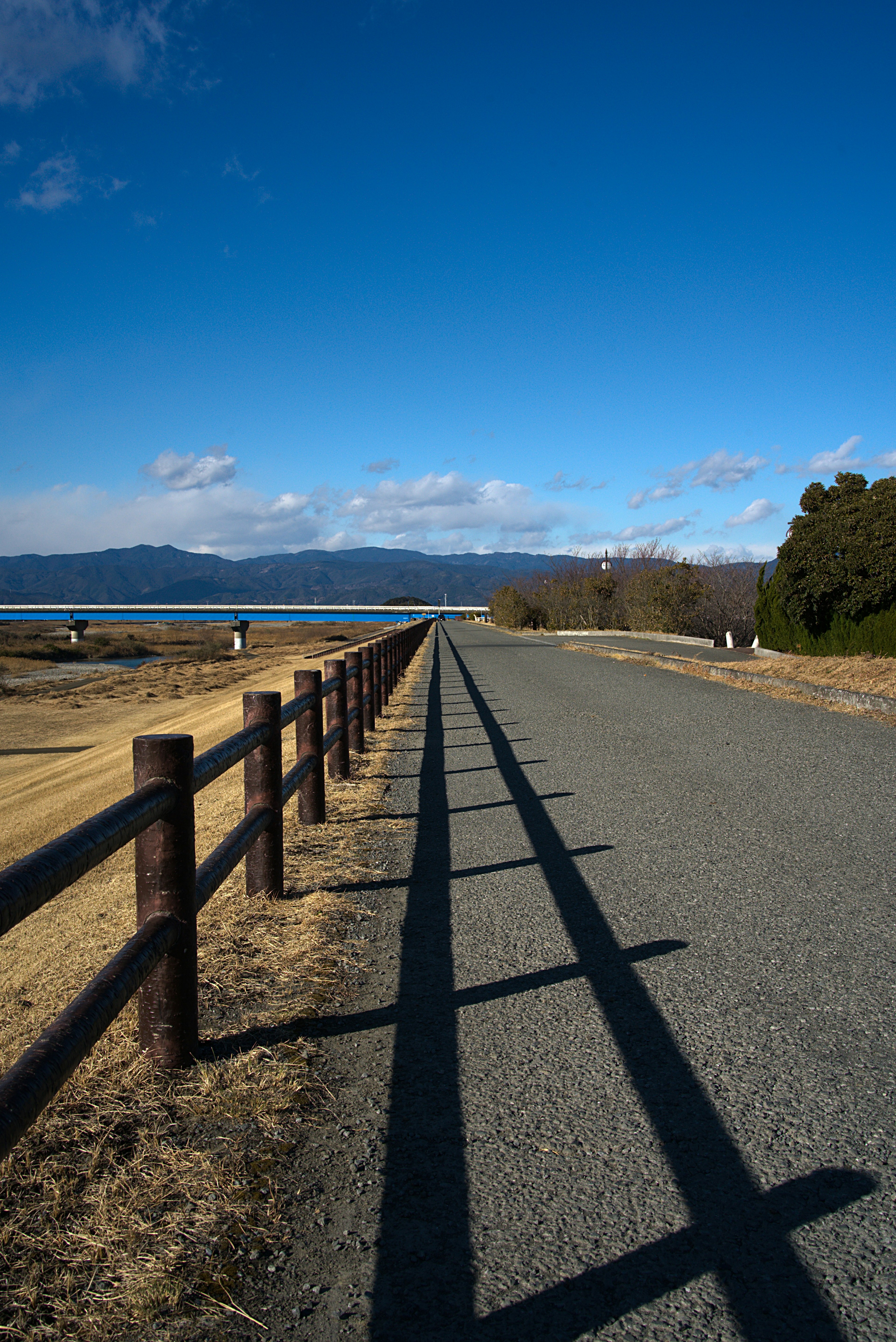 Gravel path leading towards the horizon under a blue sky with clouds