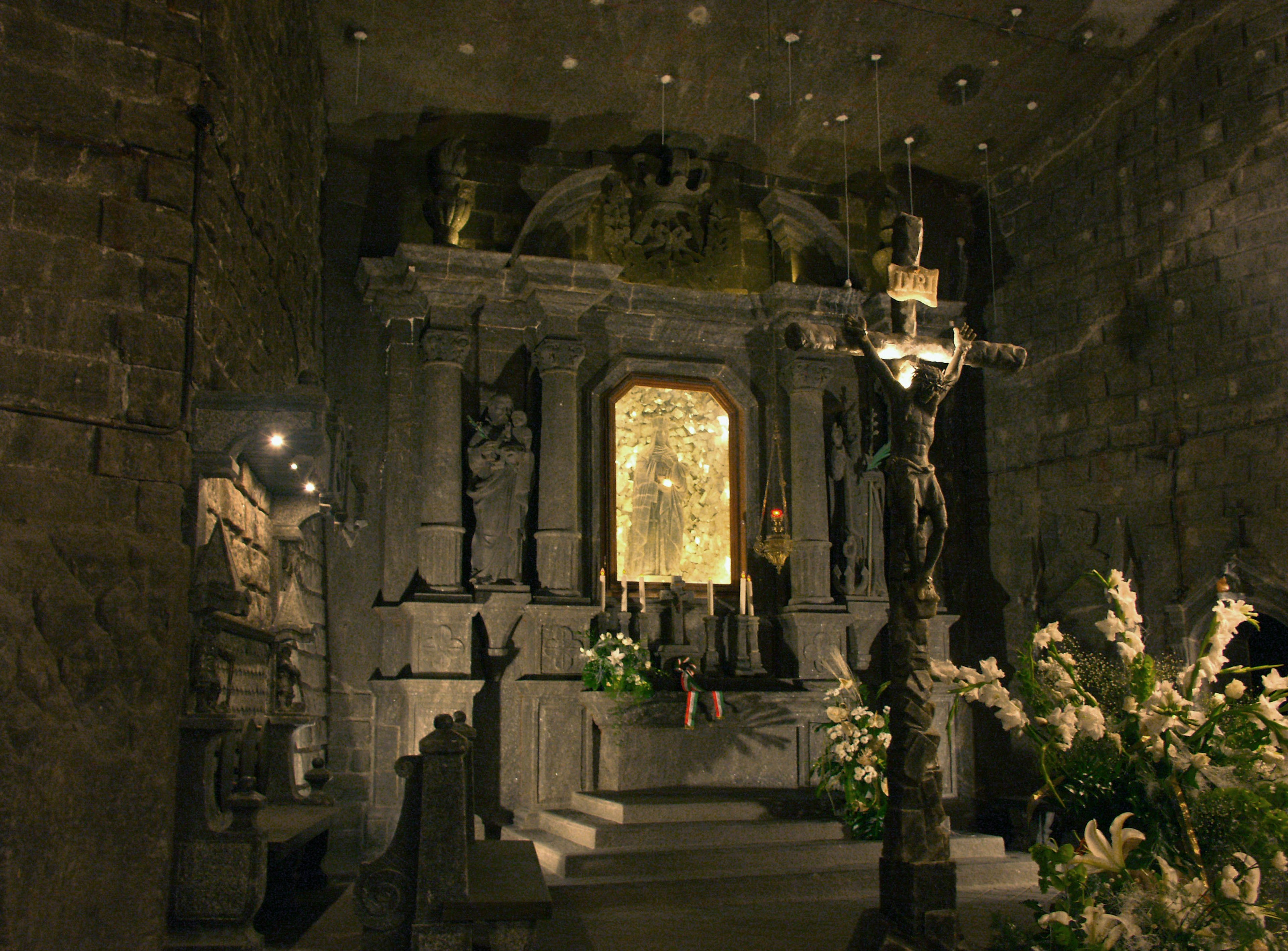 A grand altar with floral decorations in a dim stone chamber