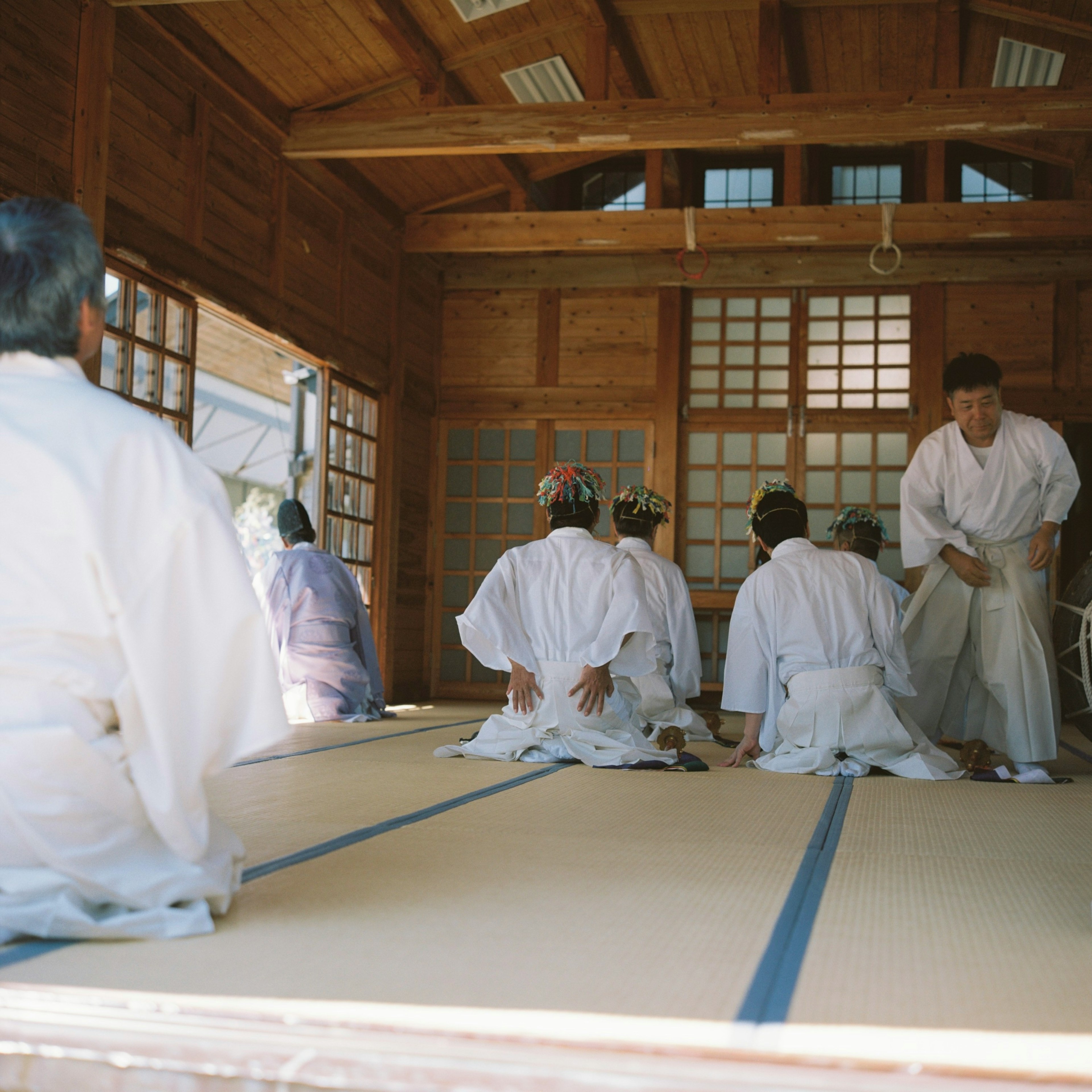 Scene of people in white garments sitting in a wooden room