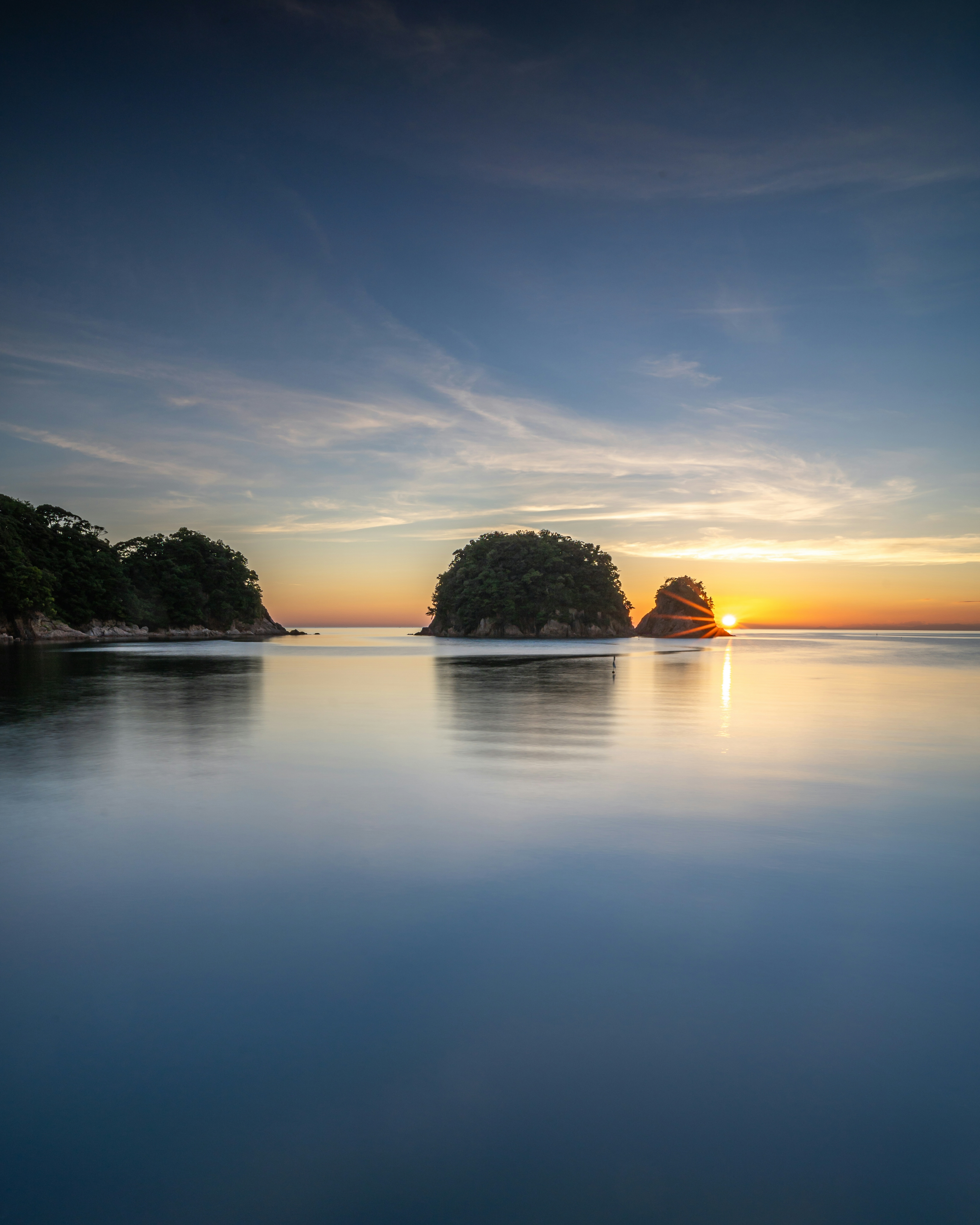 Paysage de mer calme et coucher de soleil avec de petites îles flottant sur une surface tranquille