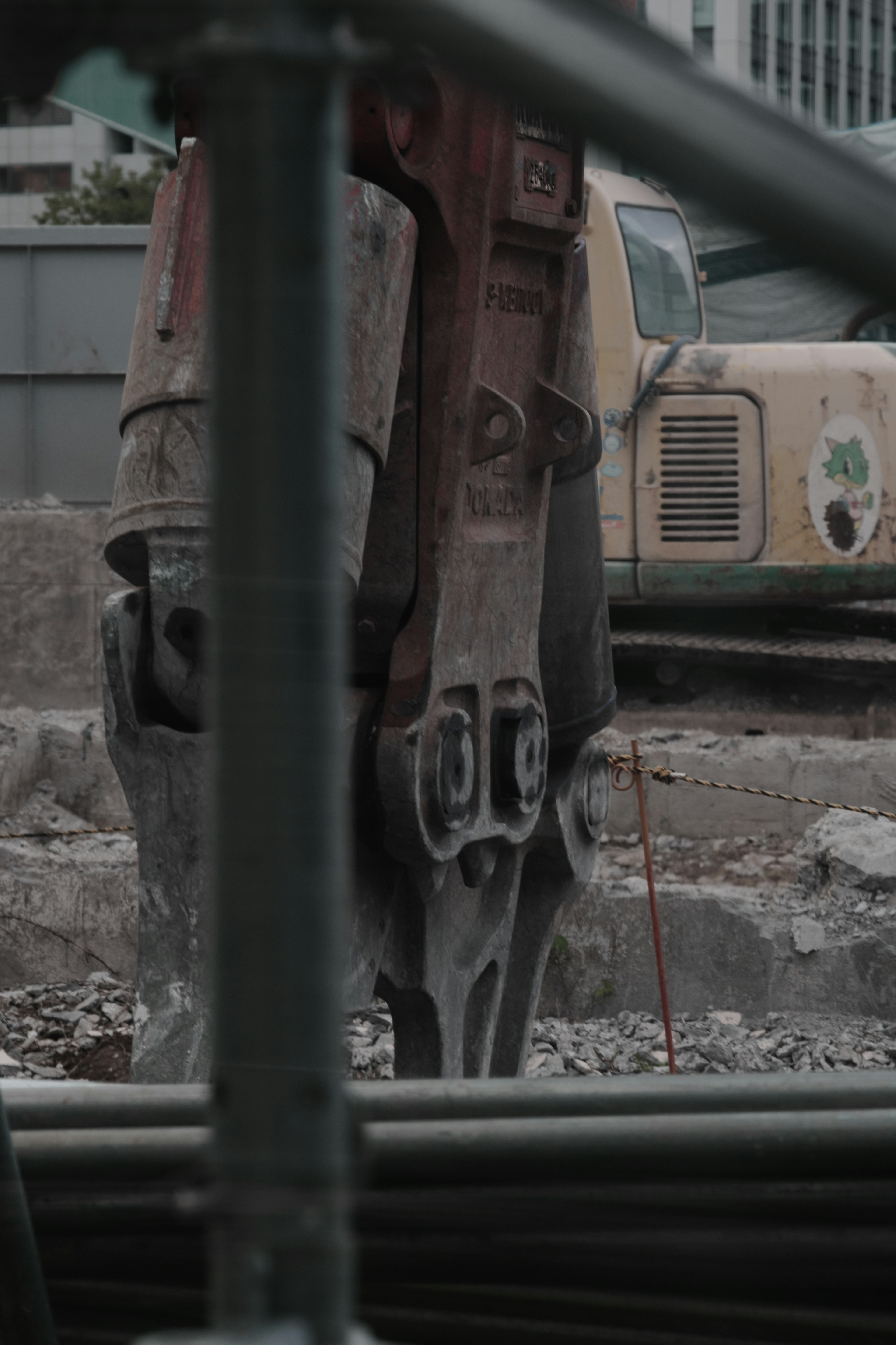 Parte de maquinaria pesada en un sitio de construcción con un camión viejo al fondo