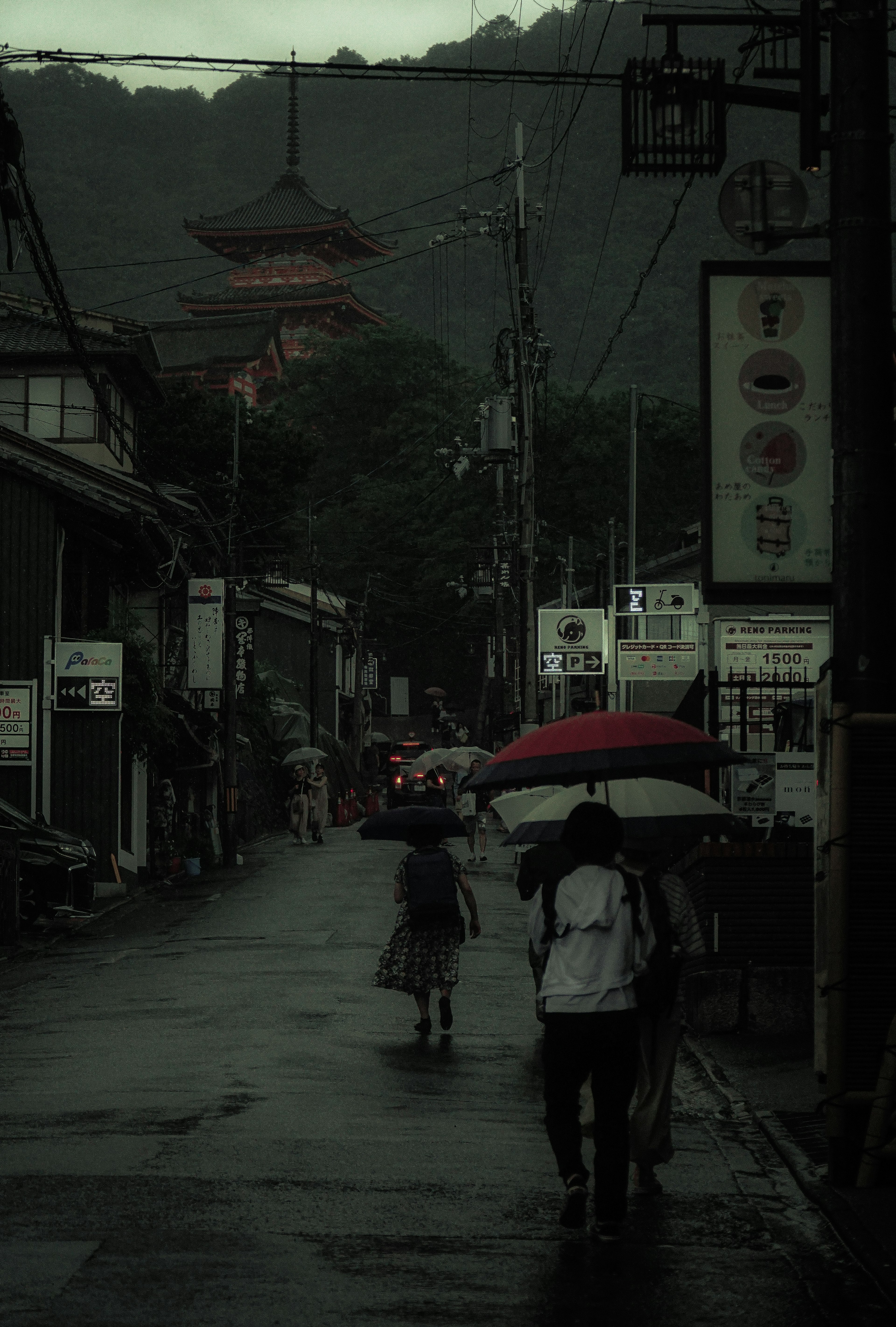 Two figures walking in the rain with umbrellas in a street scene