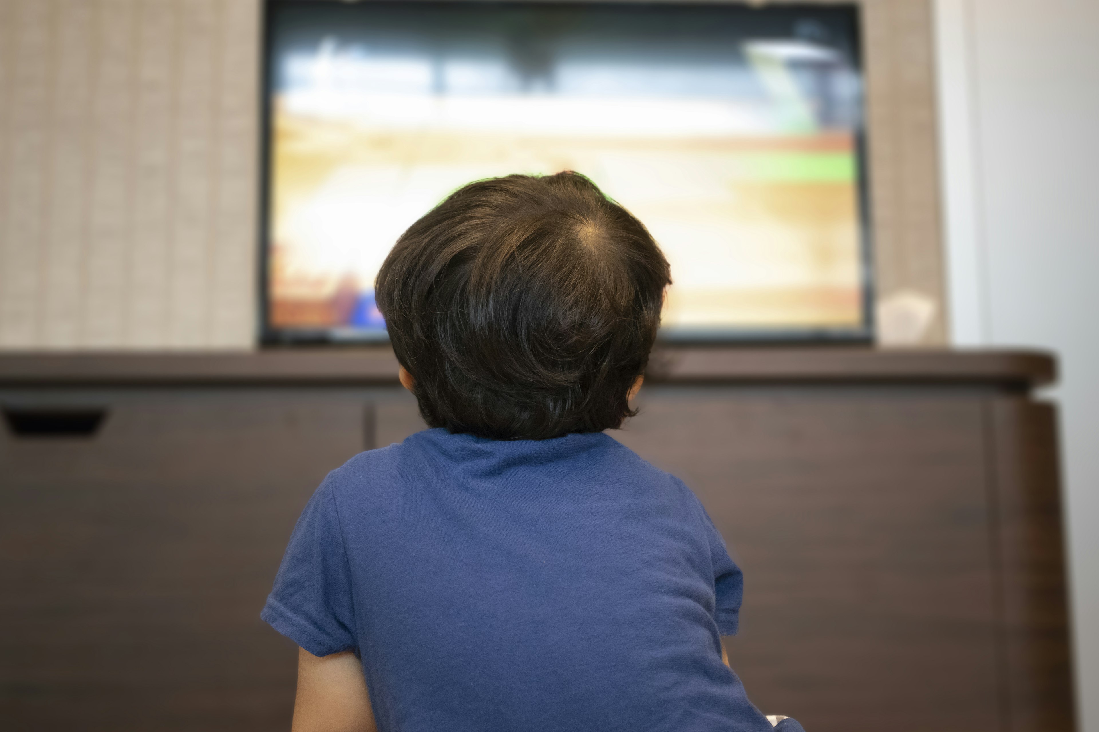 Bambino che guarda la televisione di spalle