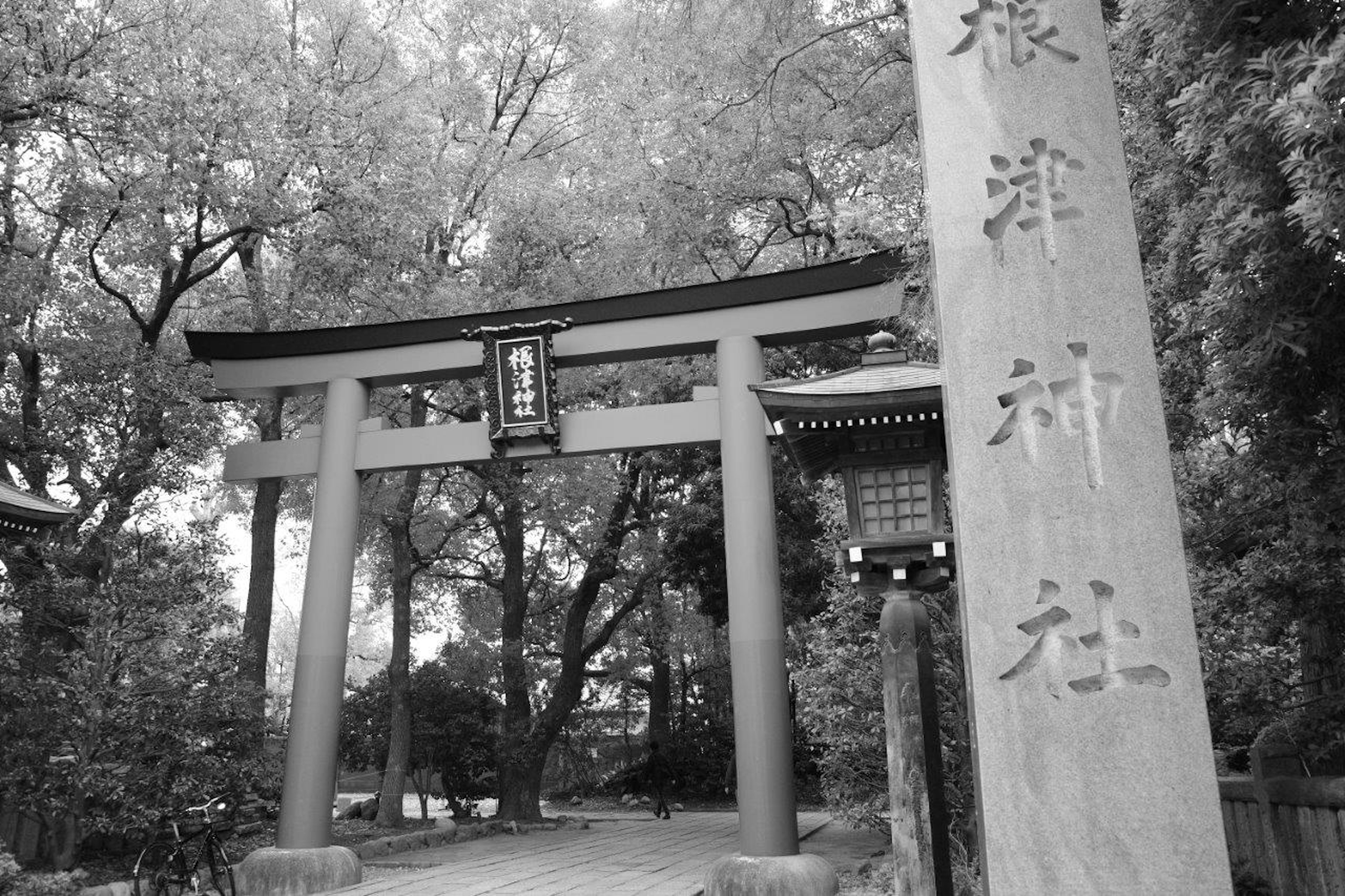 Entrada de un santuario con un torii en blanco y negro y un monumento de piedra