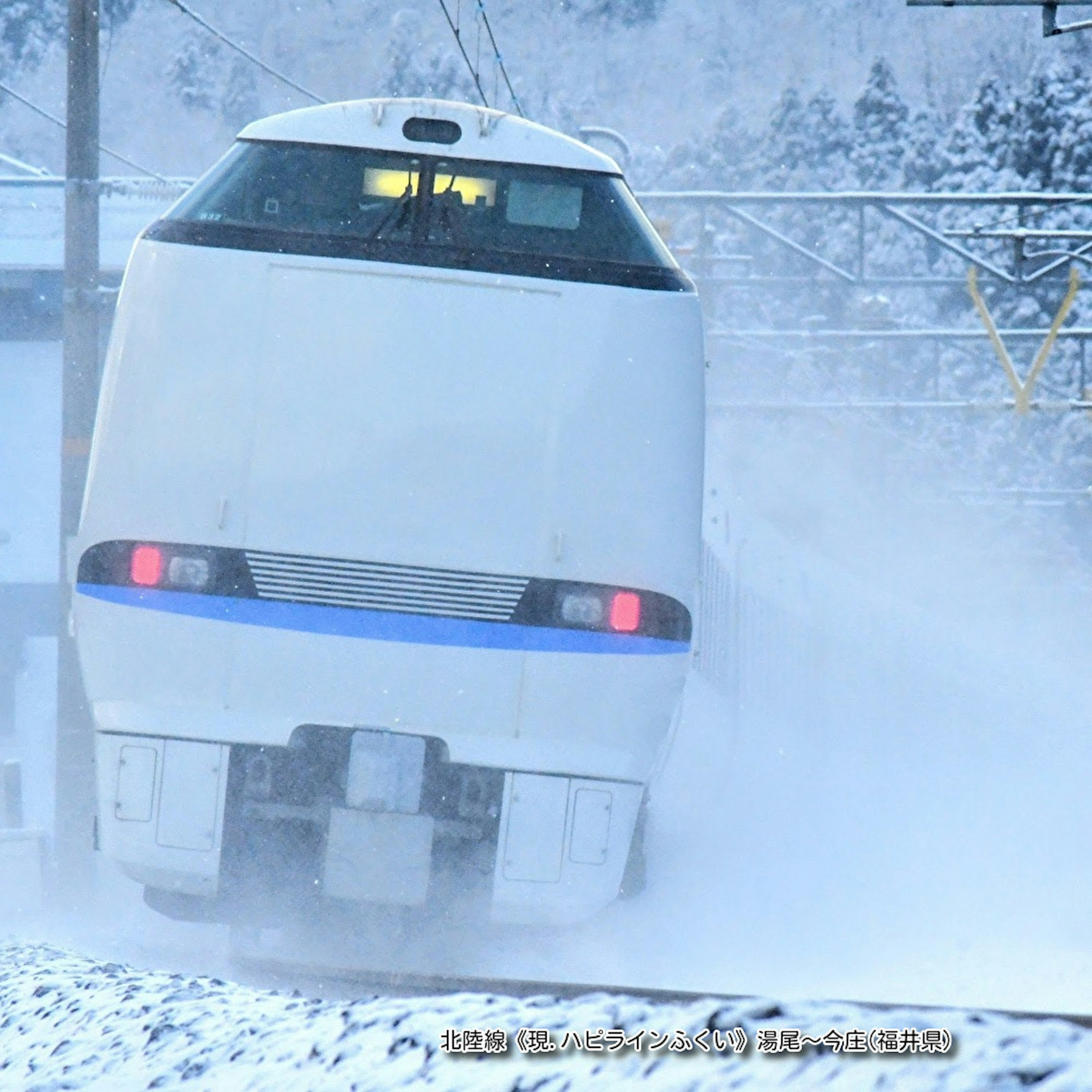 雪の中を走る白い列車の後部が見える