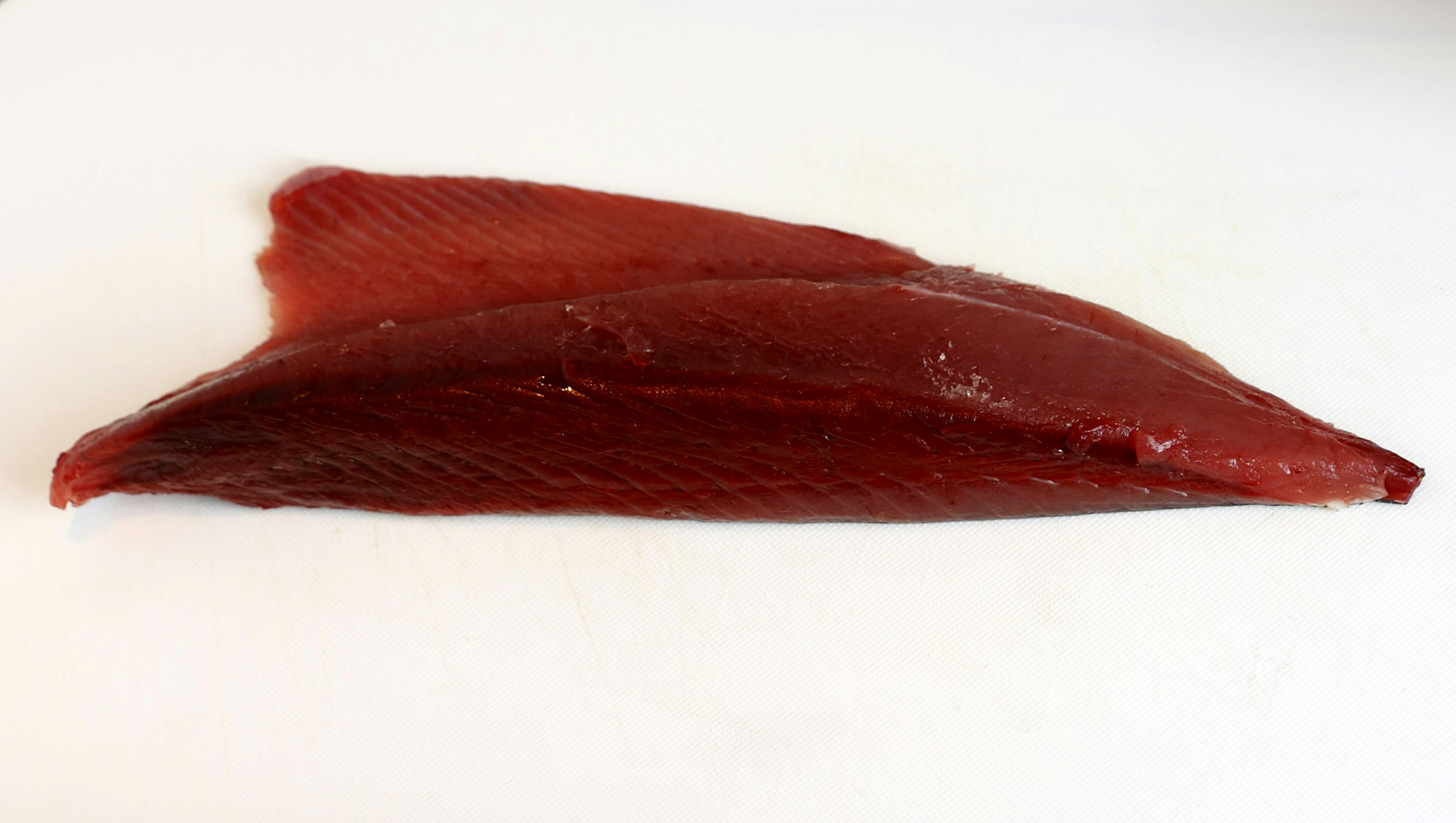 Un filete de pescado rojo brillante colocado sobre un fondo blanco