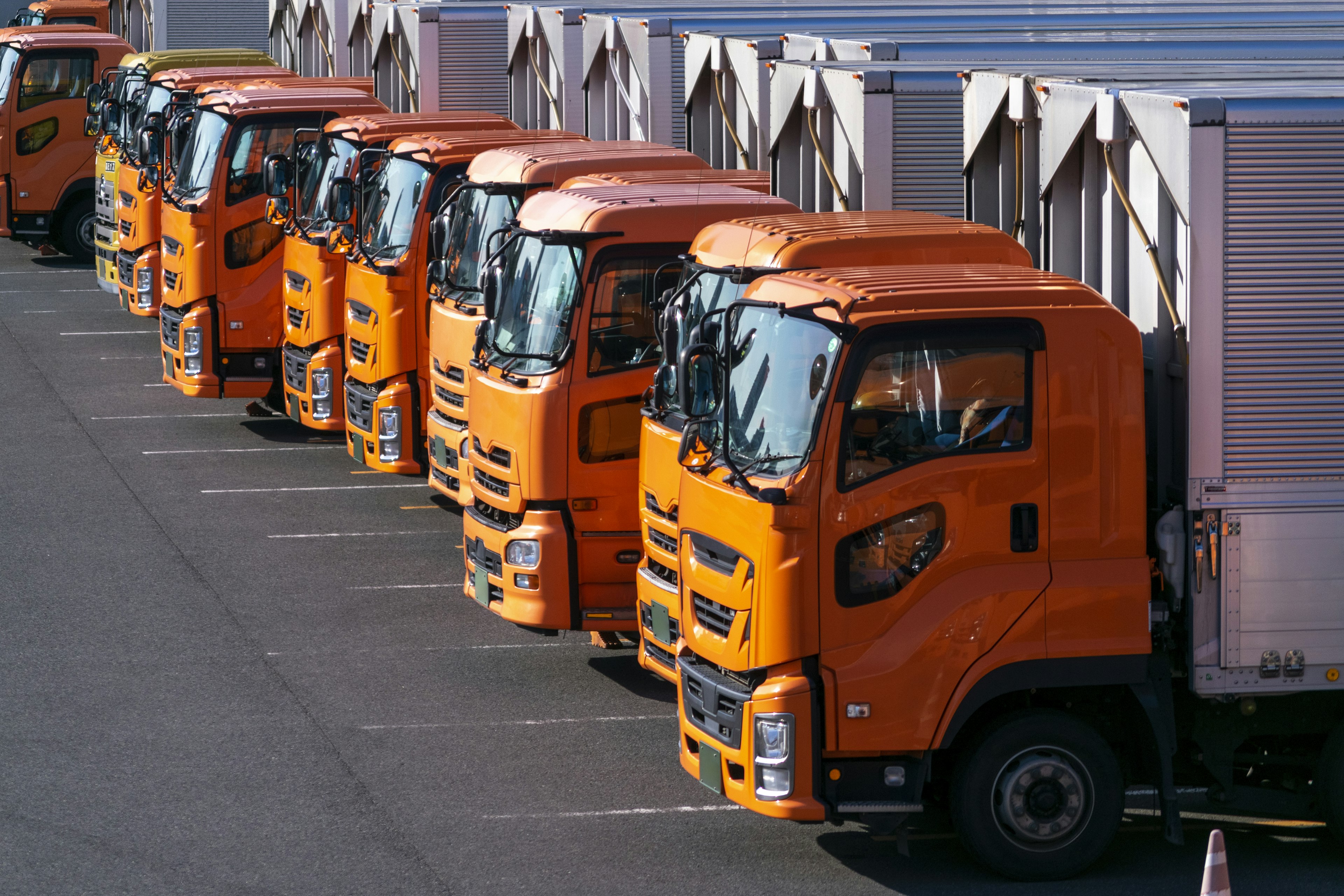 Diversi camion arancioni parcheggiati ordinatamente in un parcheggio