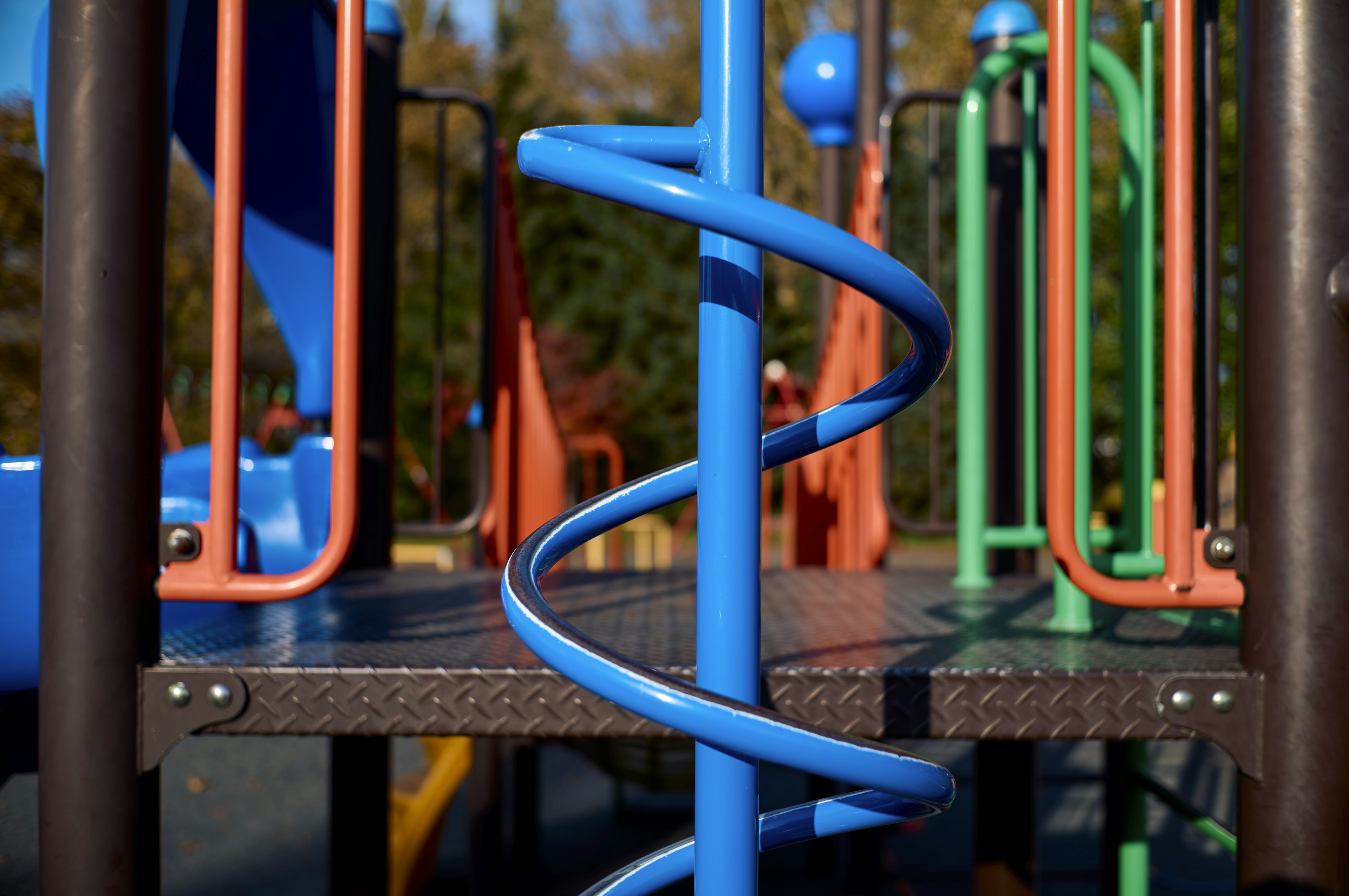 Parco giochi colorato con un palo a spirale blu e varie strutture ludiche