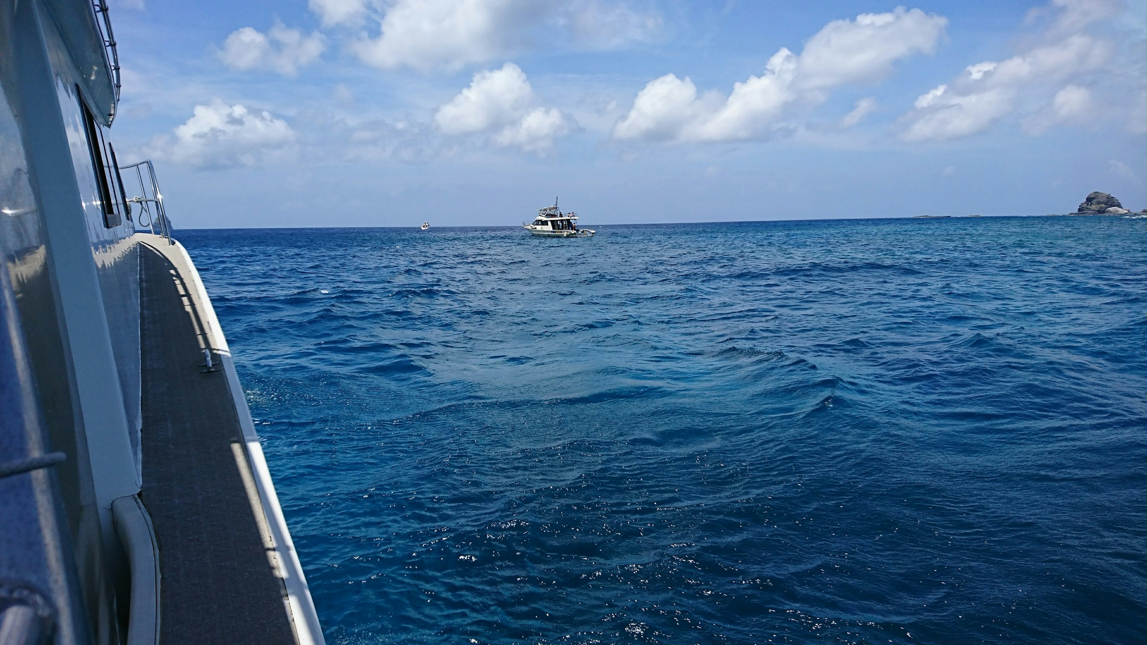 Una barca che galleggia su un mare blu sotto un cielo con nuvole bianche