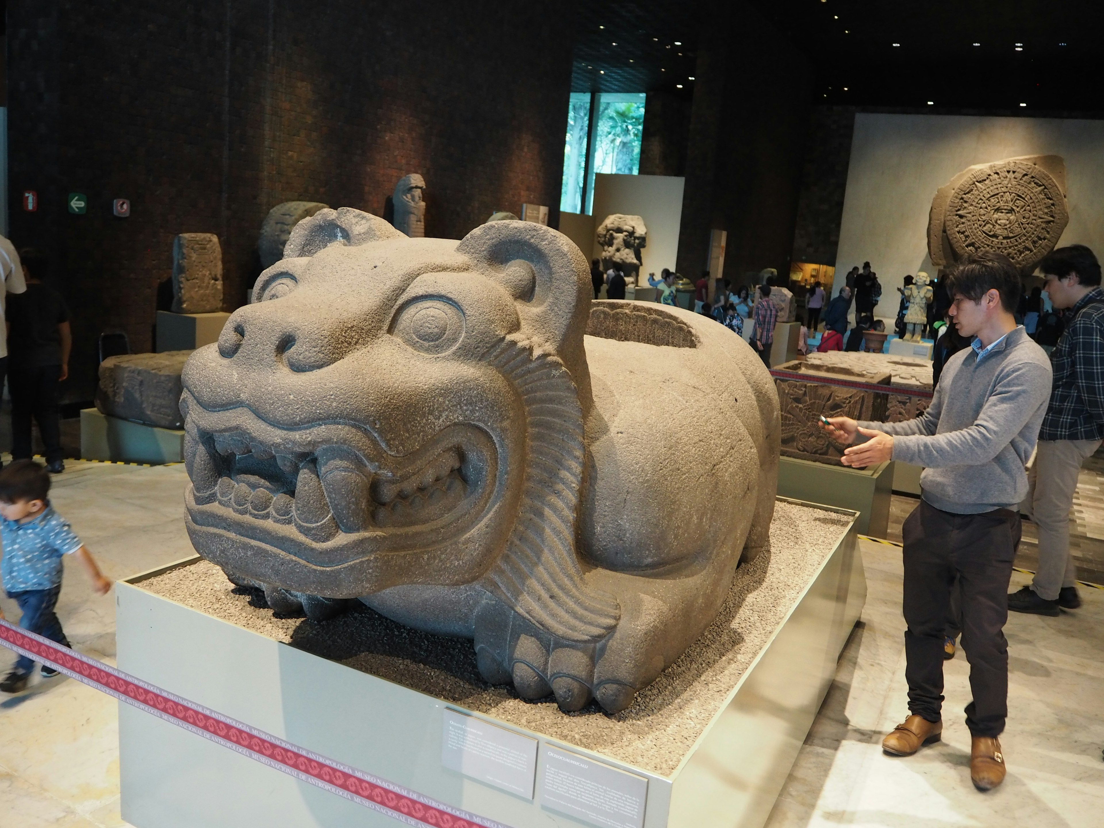 Grande scultura di bestia in pietra in un museo con visitatori