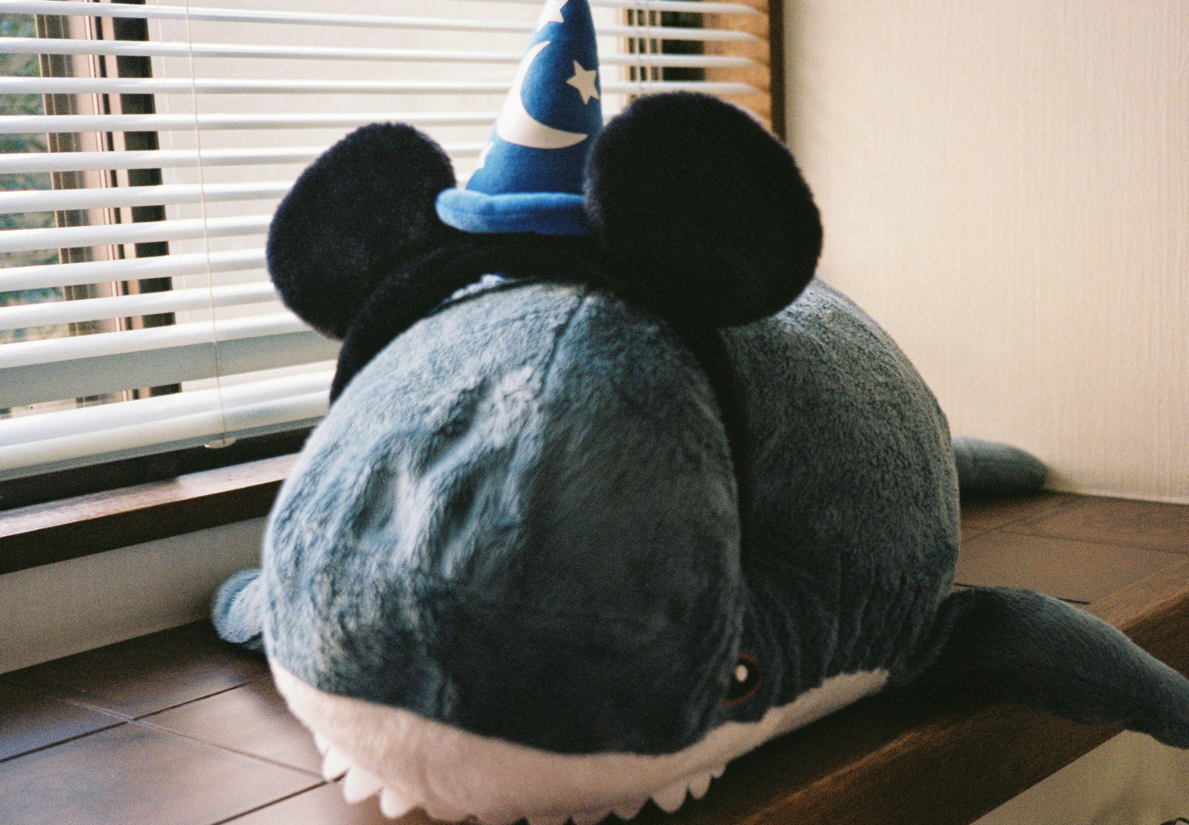 A blue plush whale wearing Mickey Mouse ears and a wizard hat