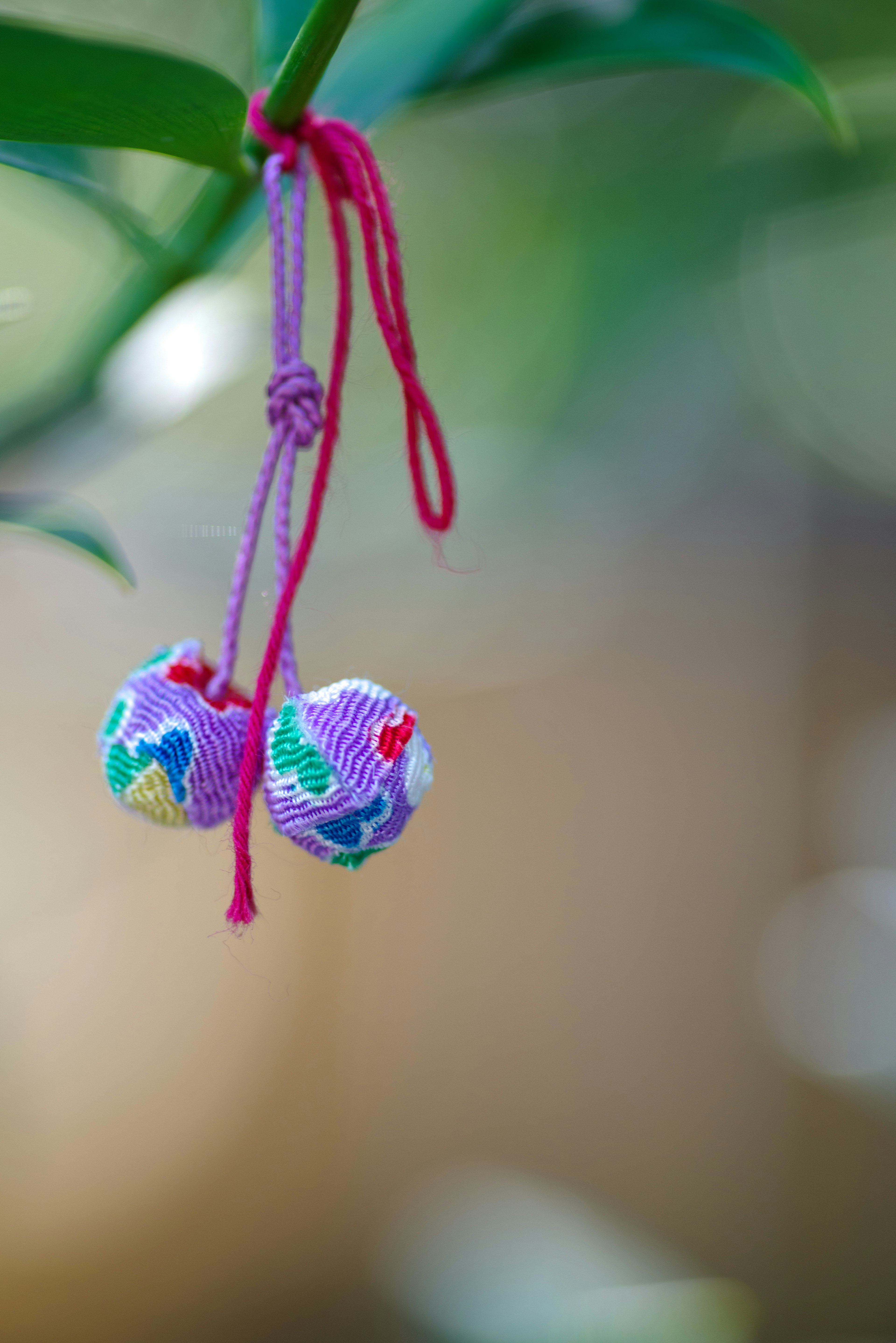 Colorful patterned bells hanging from a pink string