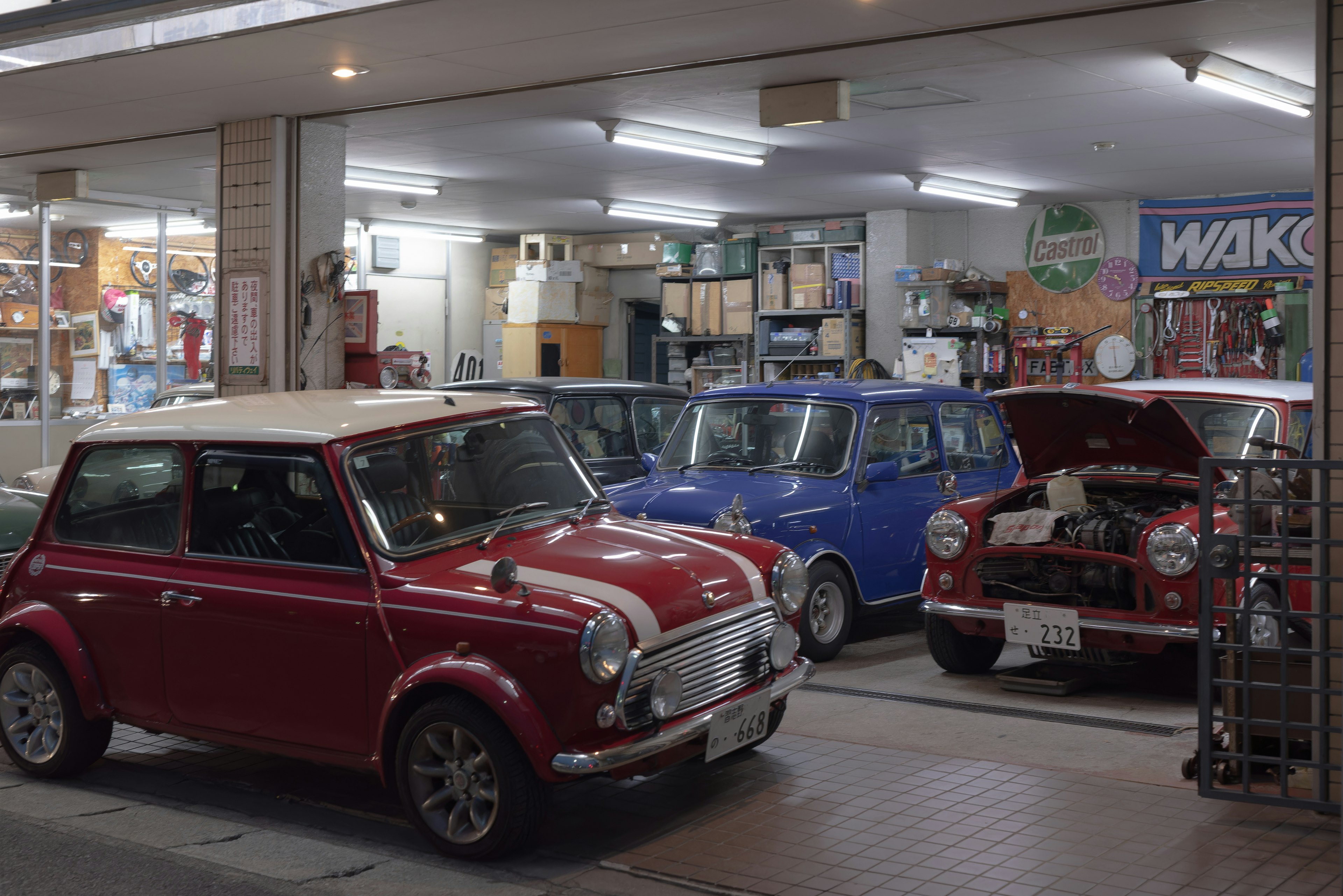 Interior bengkel dengan mobil Mini merah dan biru