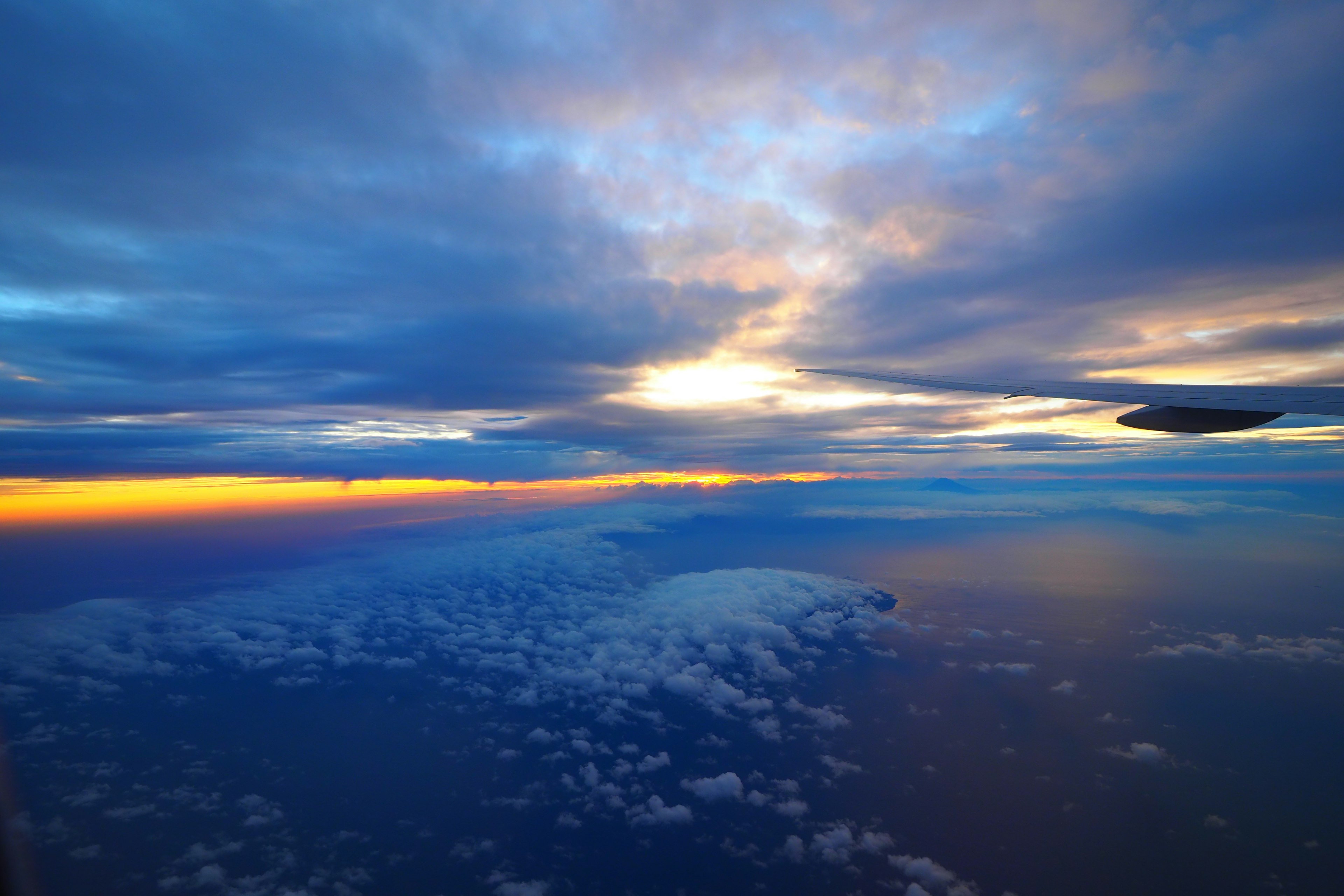 Vista aerea di un tramonto vibrante con tonalità blu e arancioni su nuvole e mare