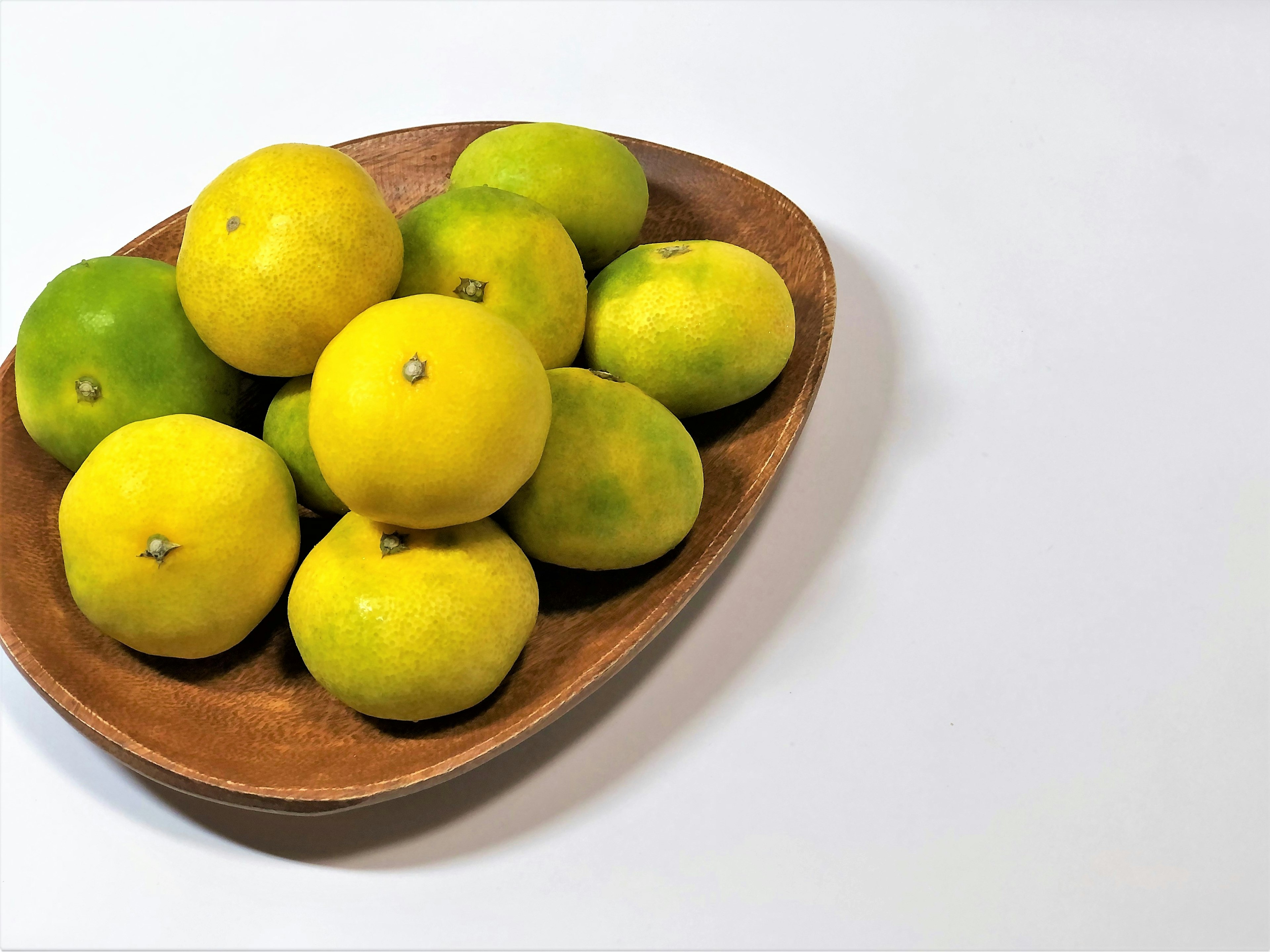 Limoni e lime gialli e verdi in una ciotola di legno