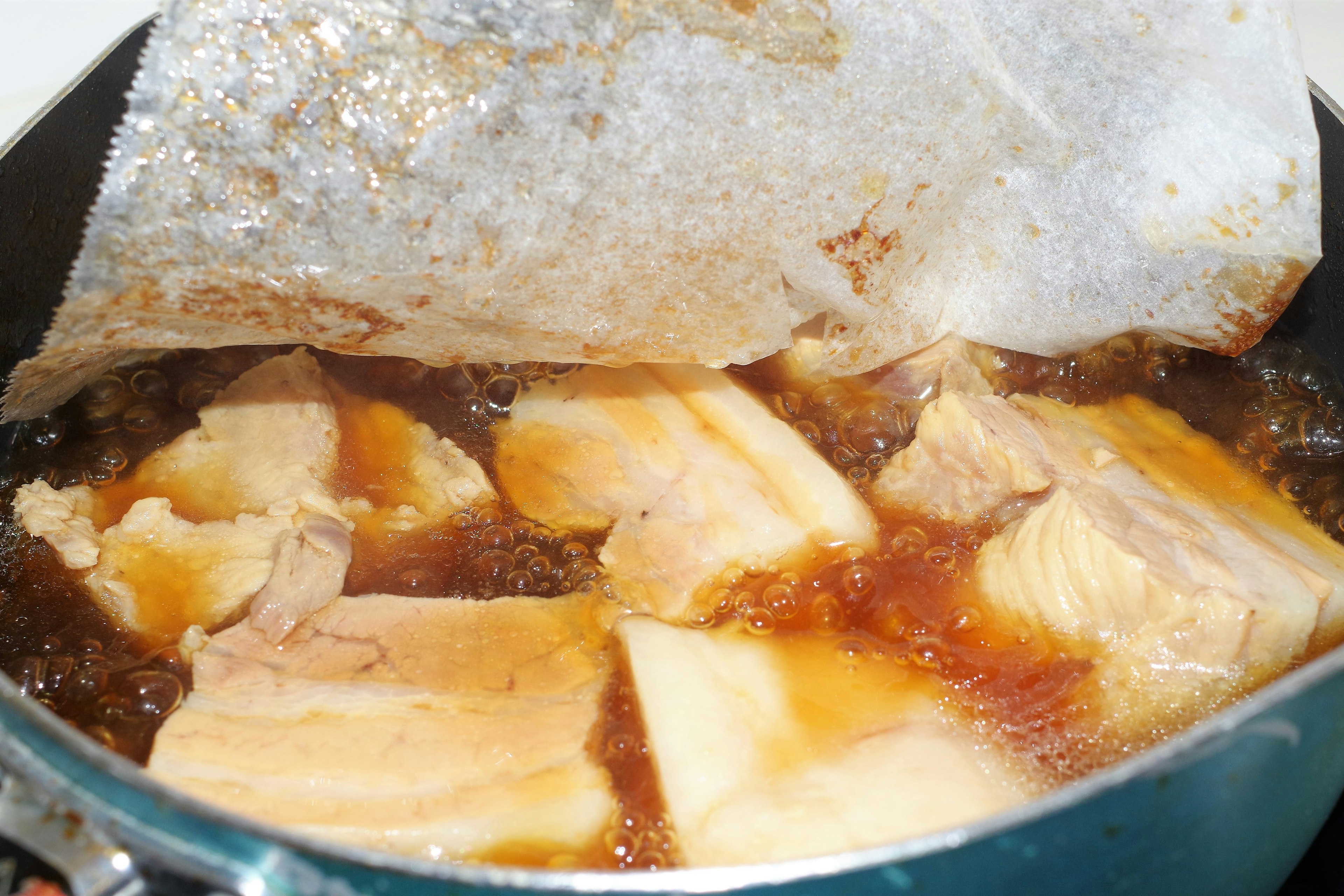 Chunks of pork simmering in a pot with seasoning