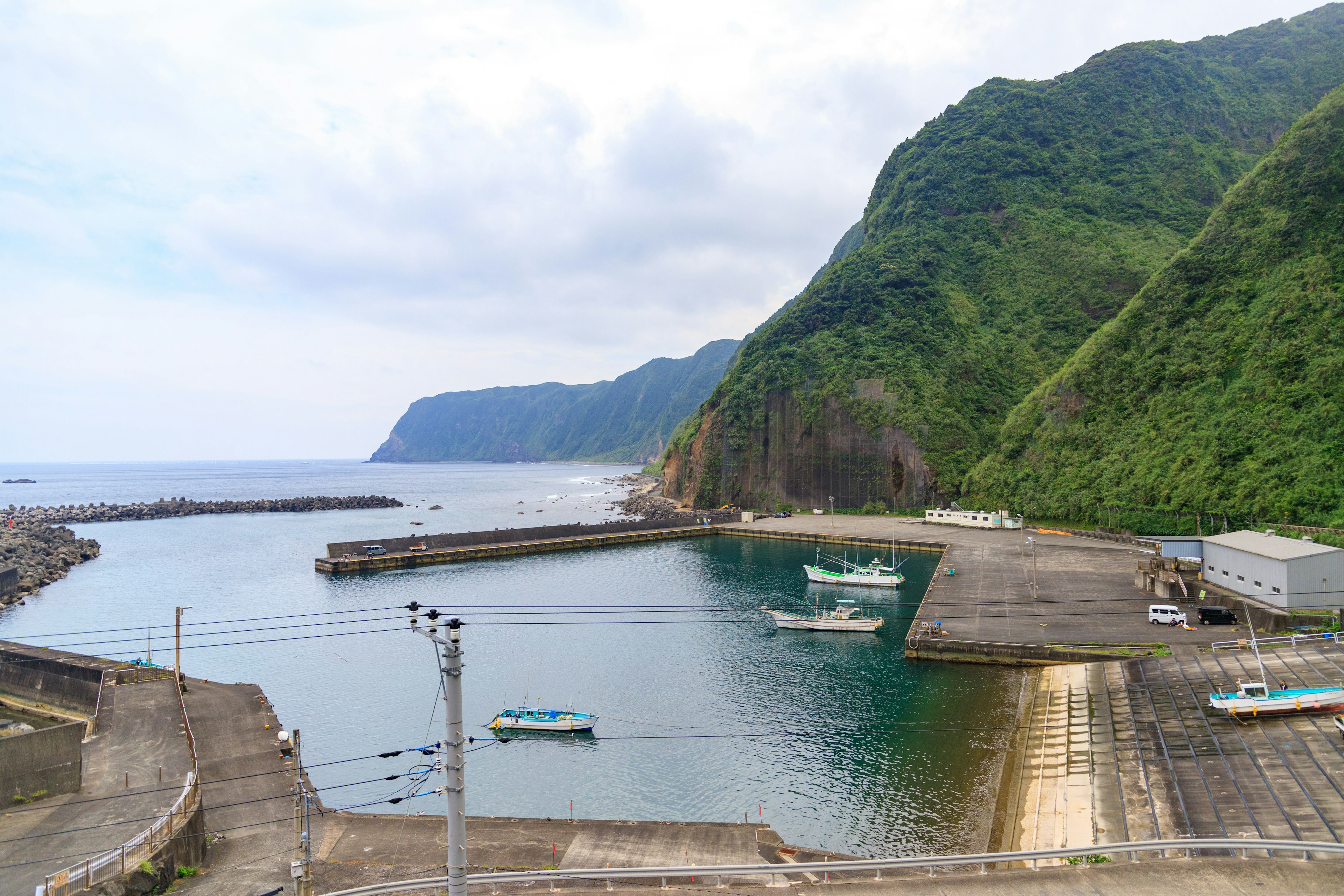 Quiet harbor surrounded by green mountains with small boats