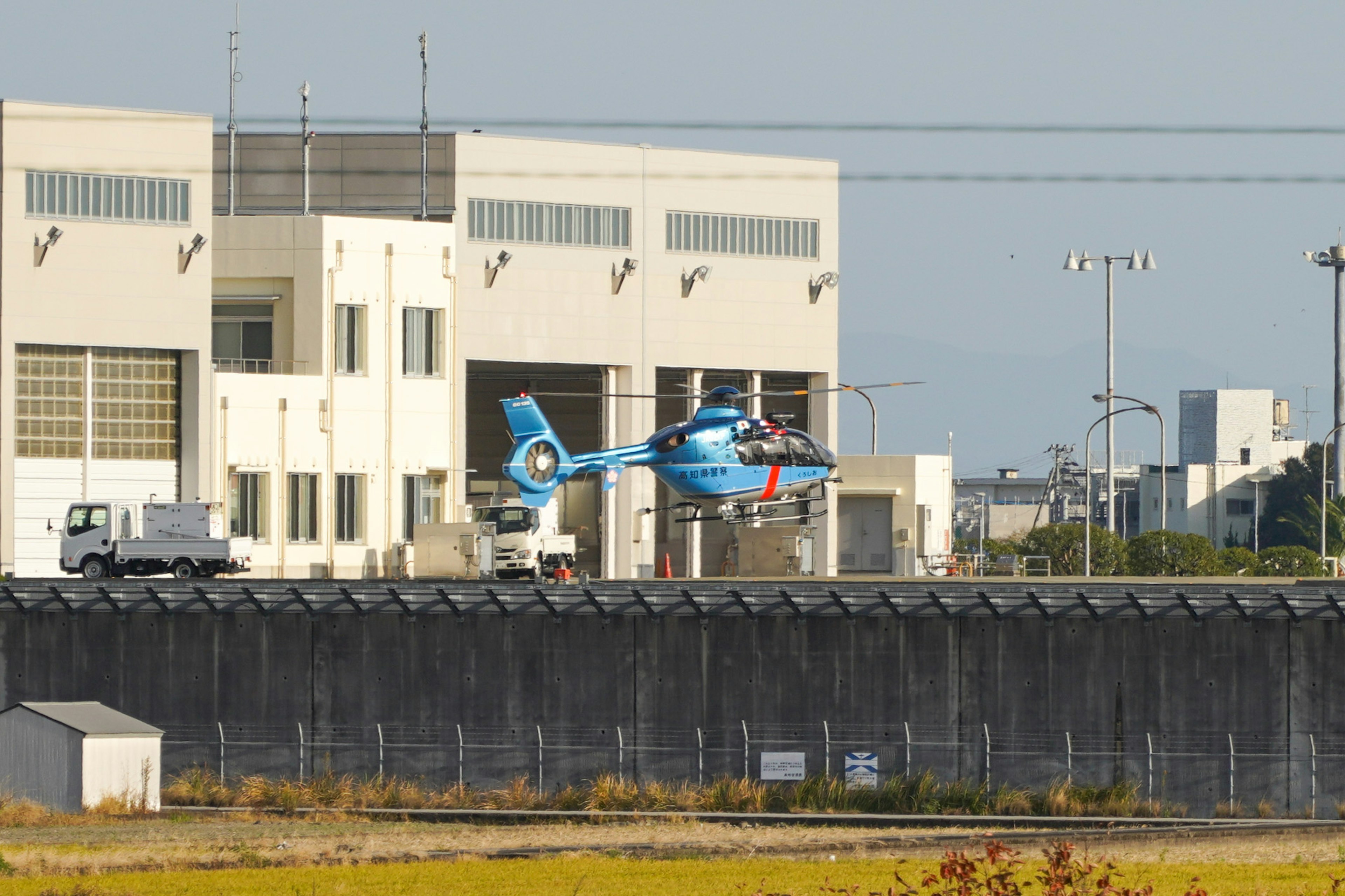 A blue helicopter taking off near a building