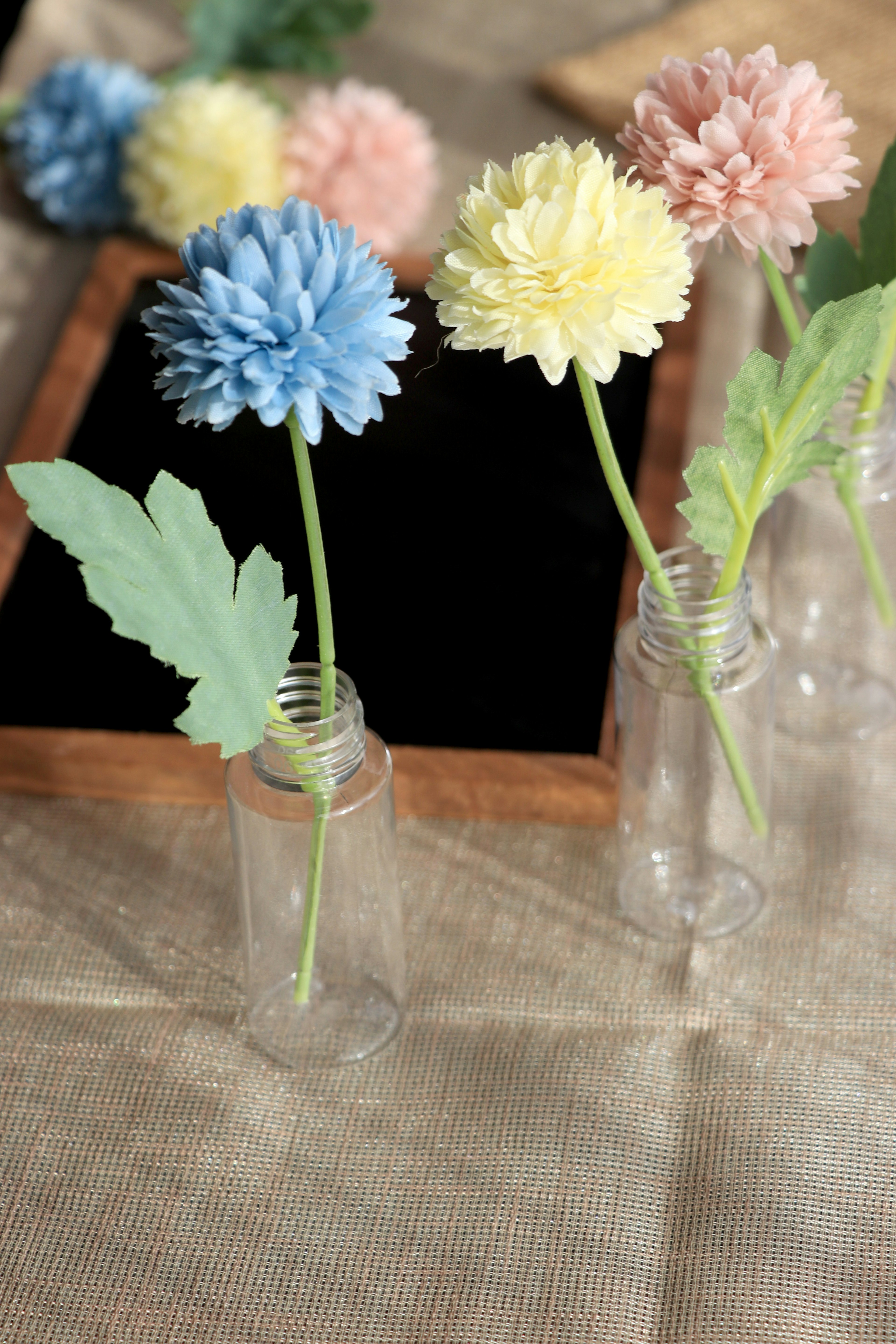 Blaue gelbe und rosa Blumen in kleinen Flaschen auf einem Tisch