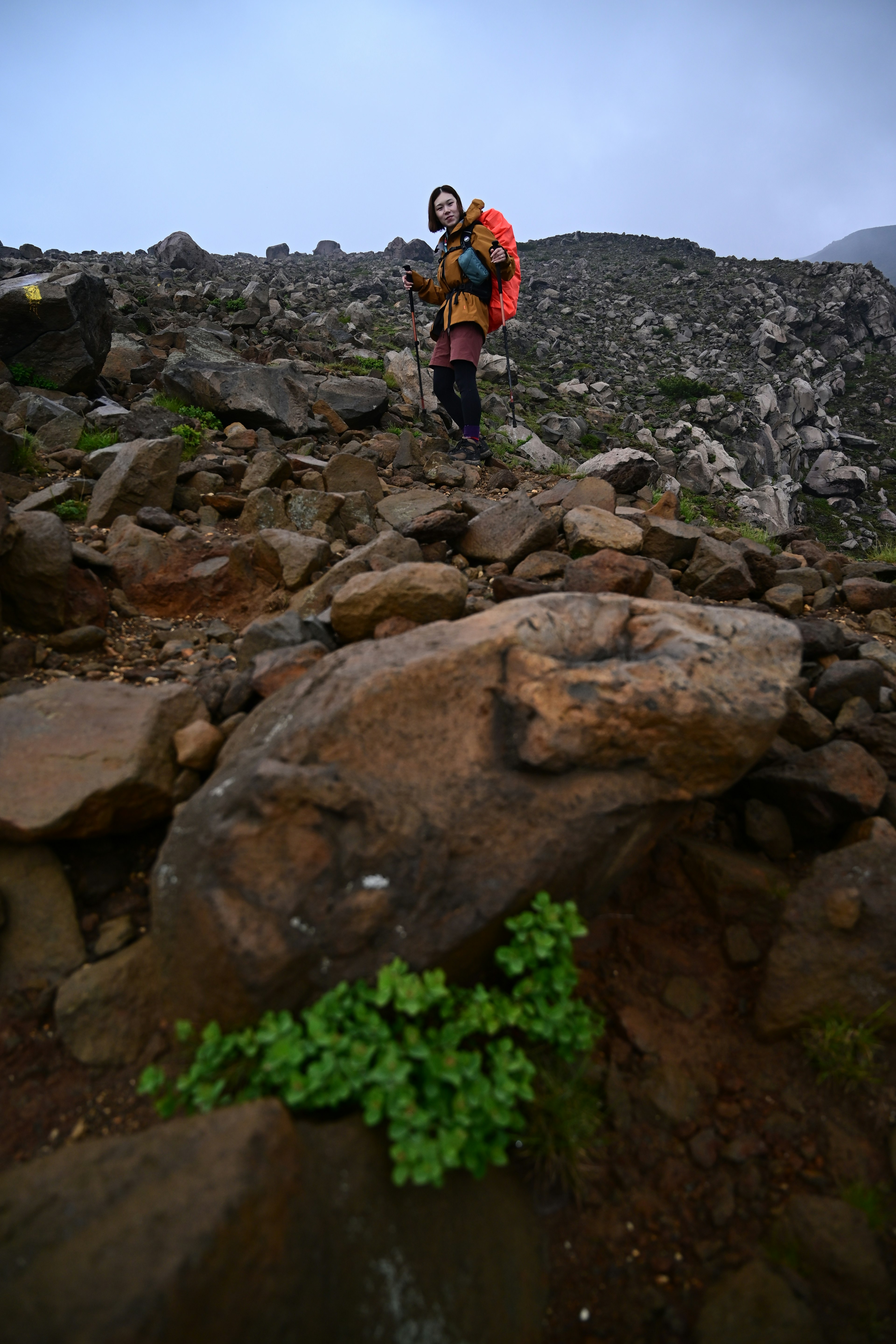 Hiker standing on rocky terrain with a backpack in a mountainous landscape