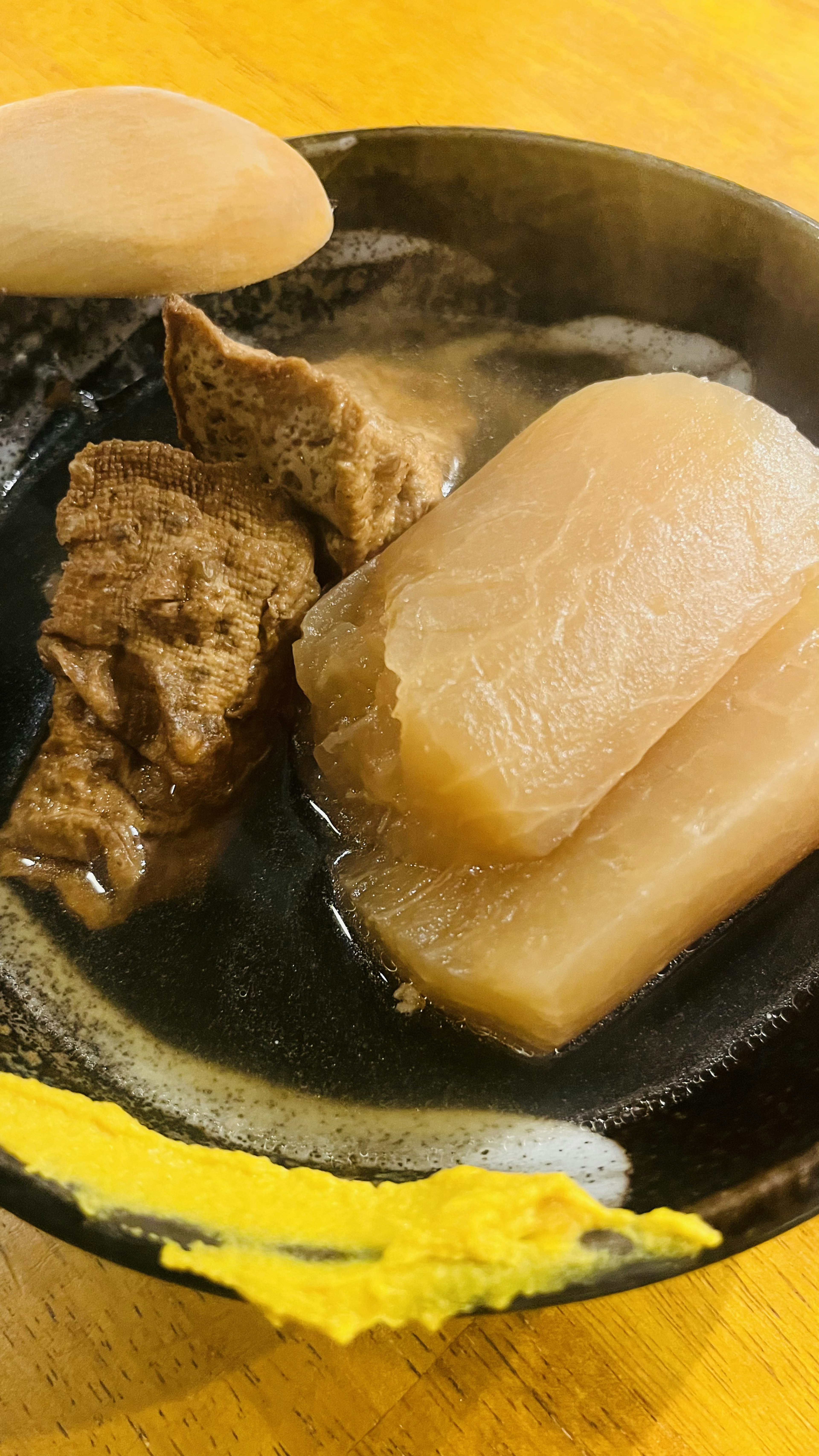 Braised daikon and meat in a black bowl