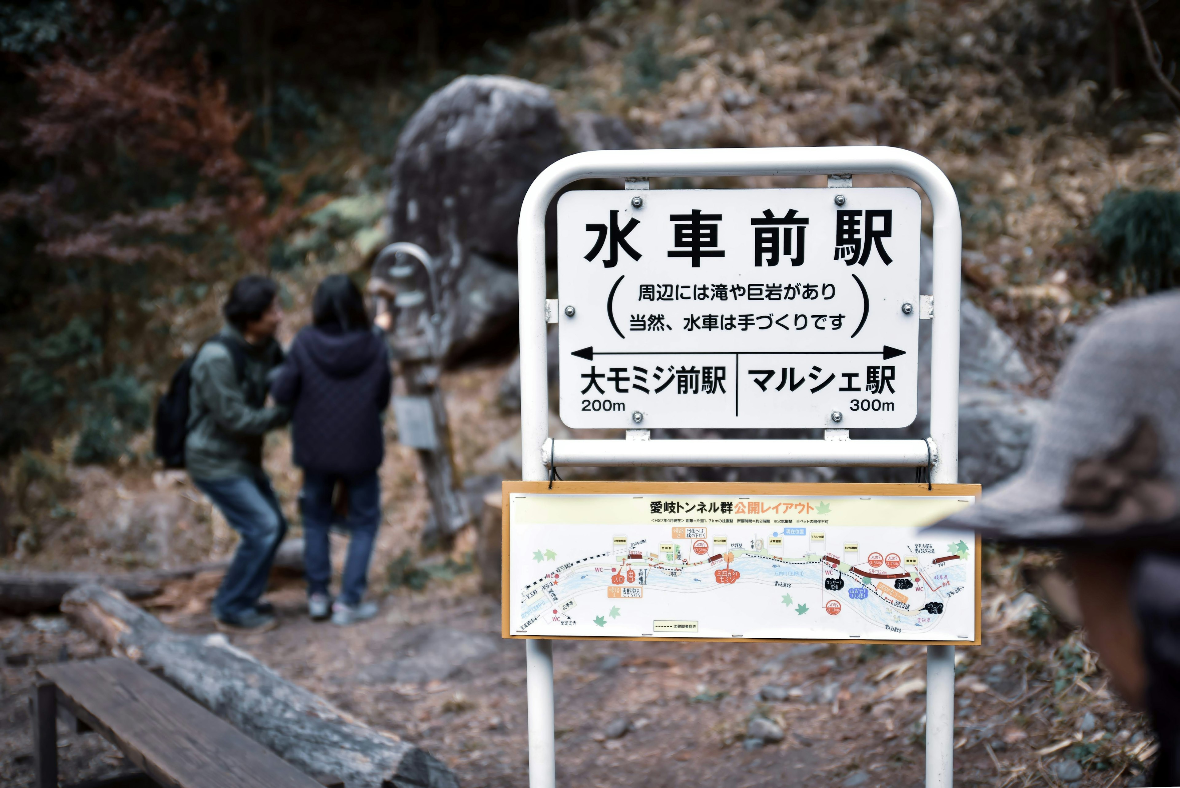 水车前站的标志牌和背景中的两名游客