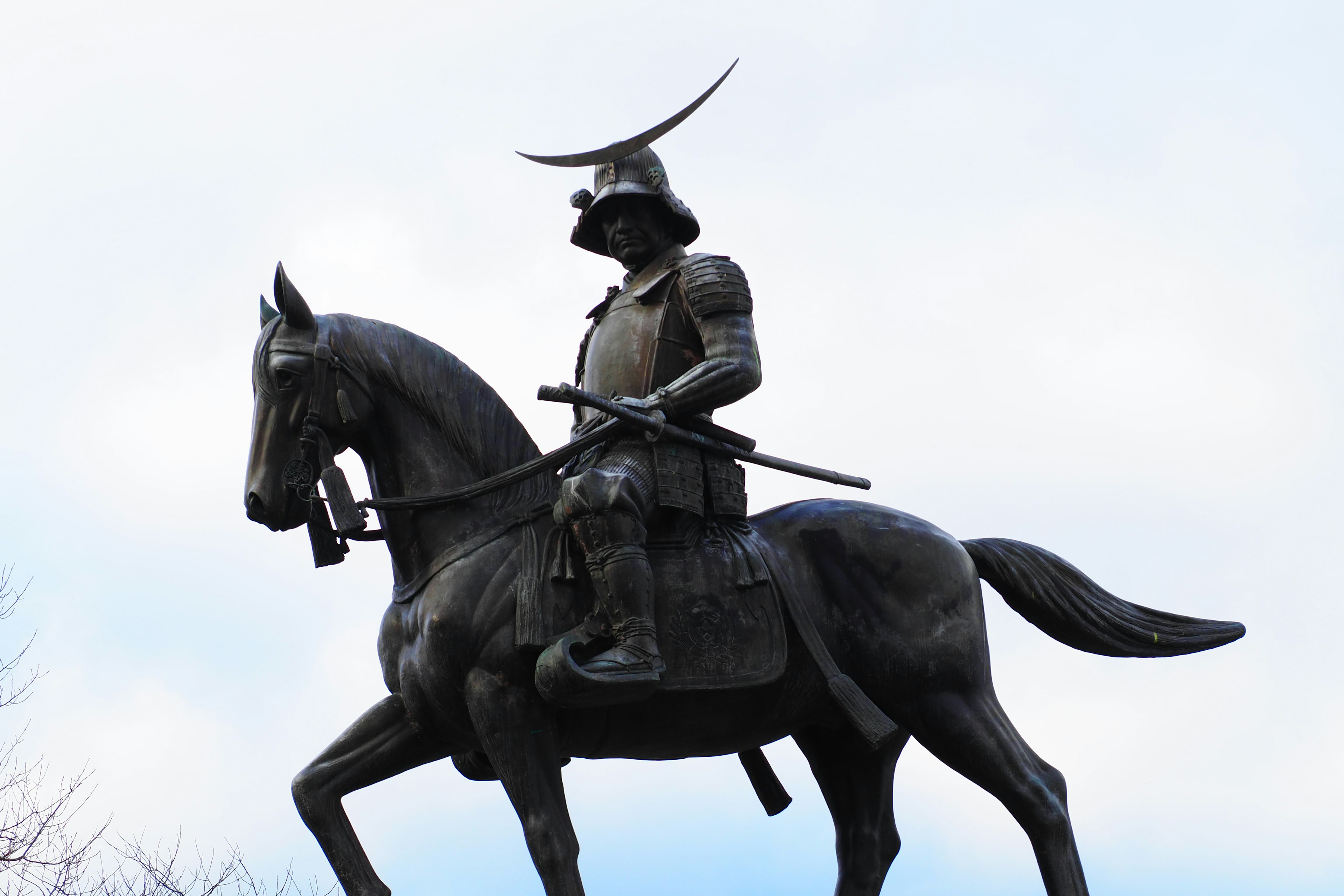 Bronze statue of a mounted samurai under a blue sky