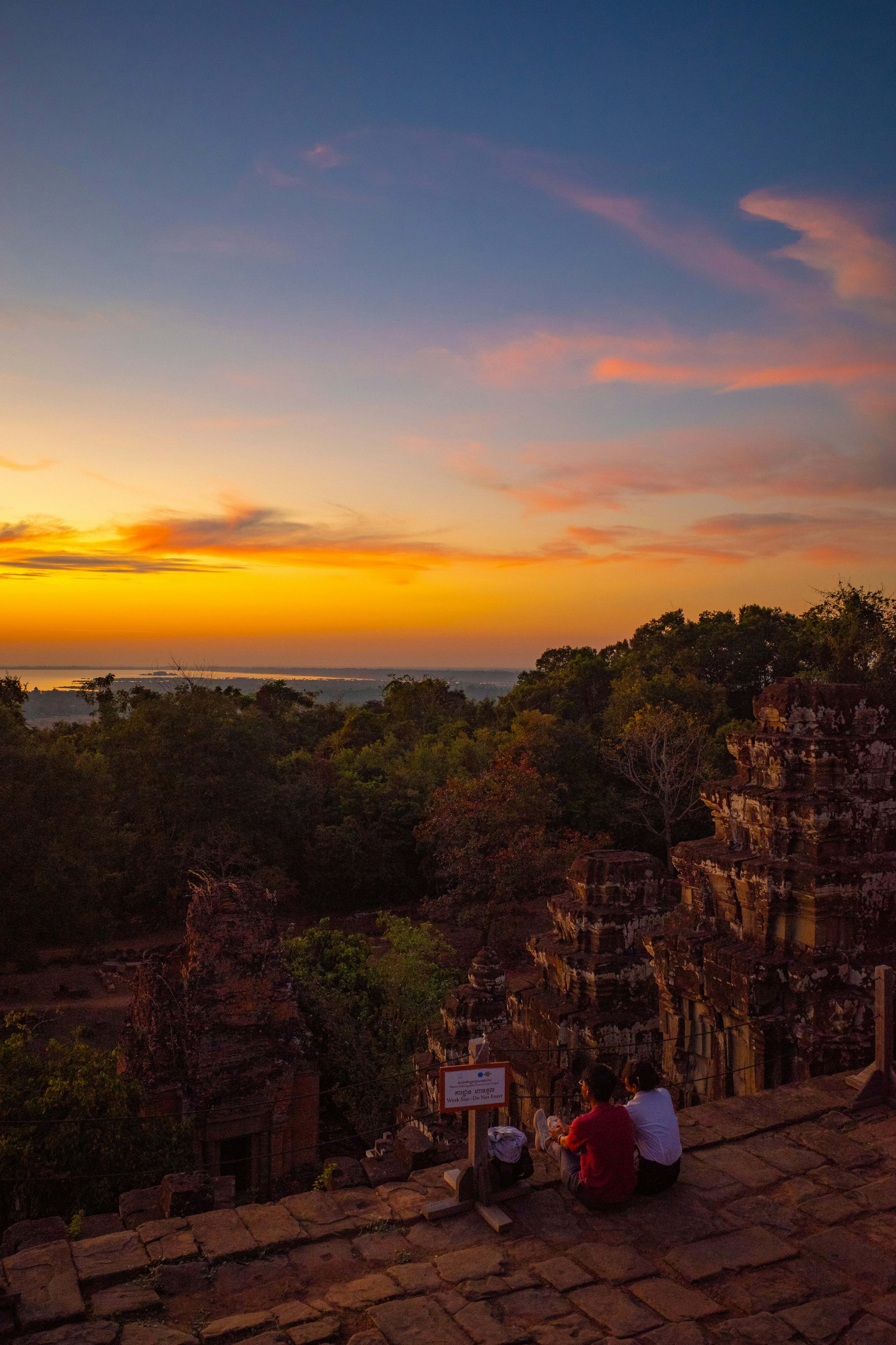 Two people watching the sunset over ancient ruins