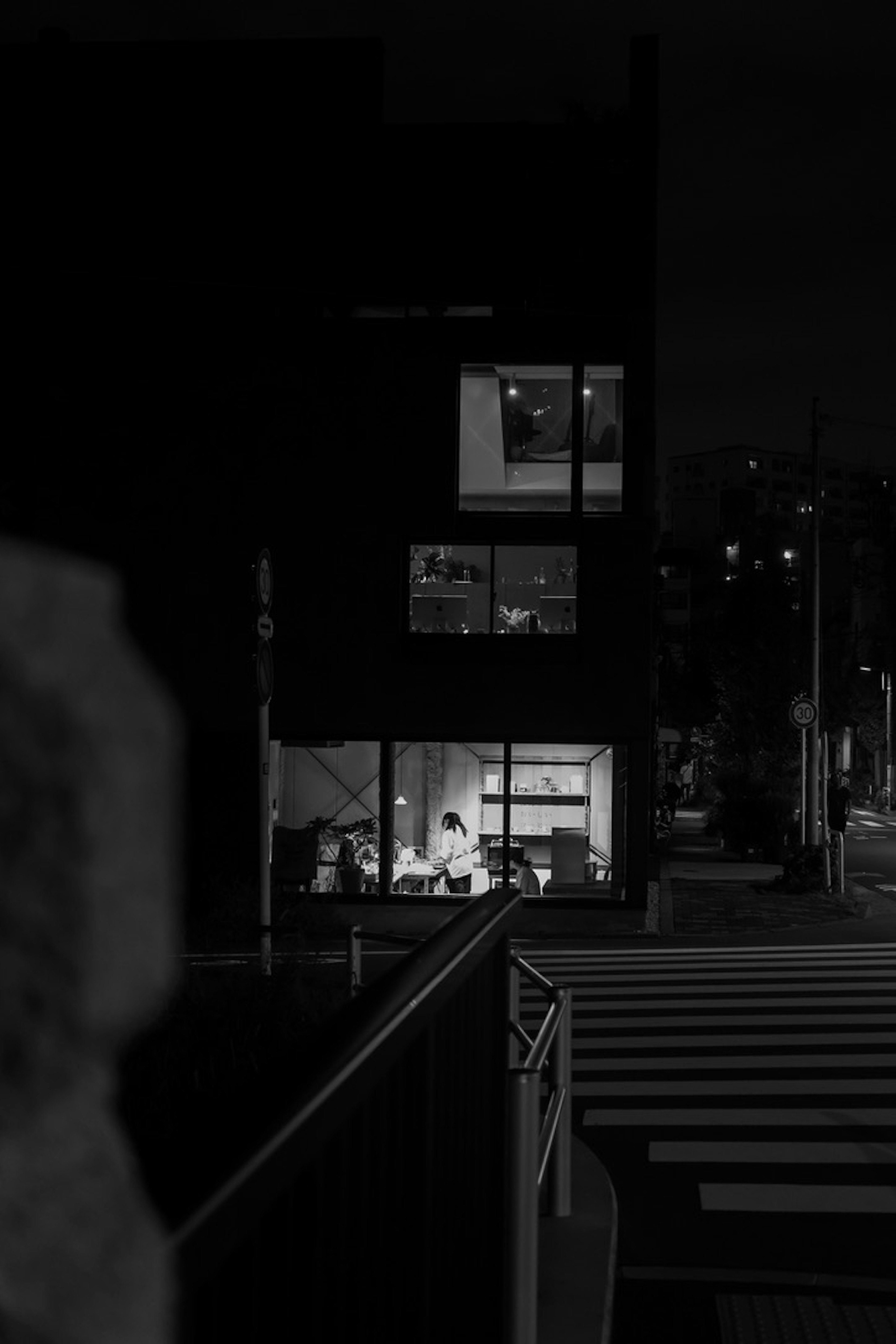 Dark building at night with illuminated windows showing people inside