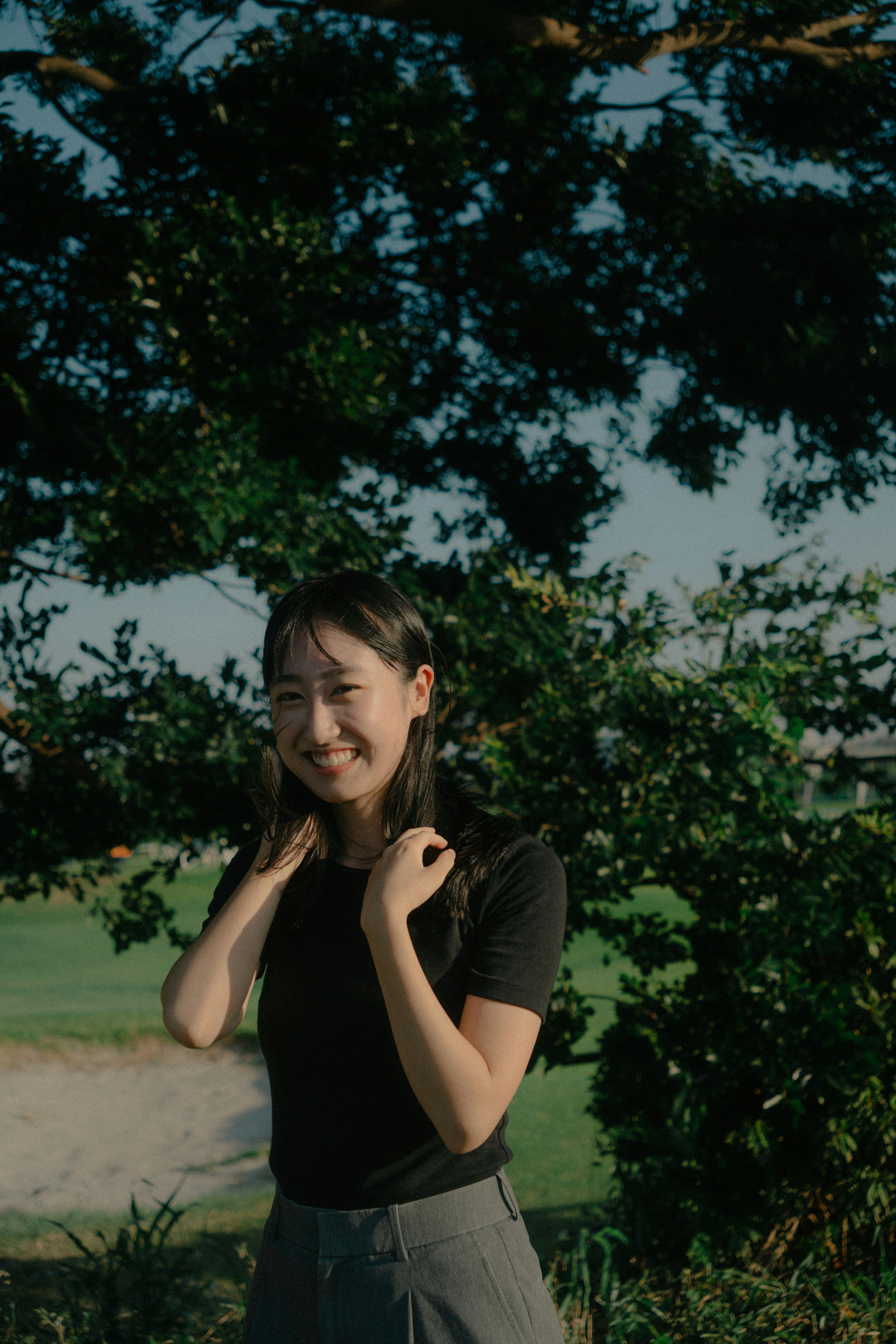 Young woman smiling in a black top surrounded by greenery