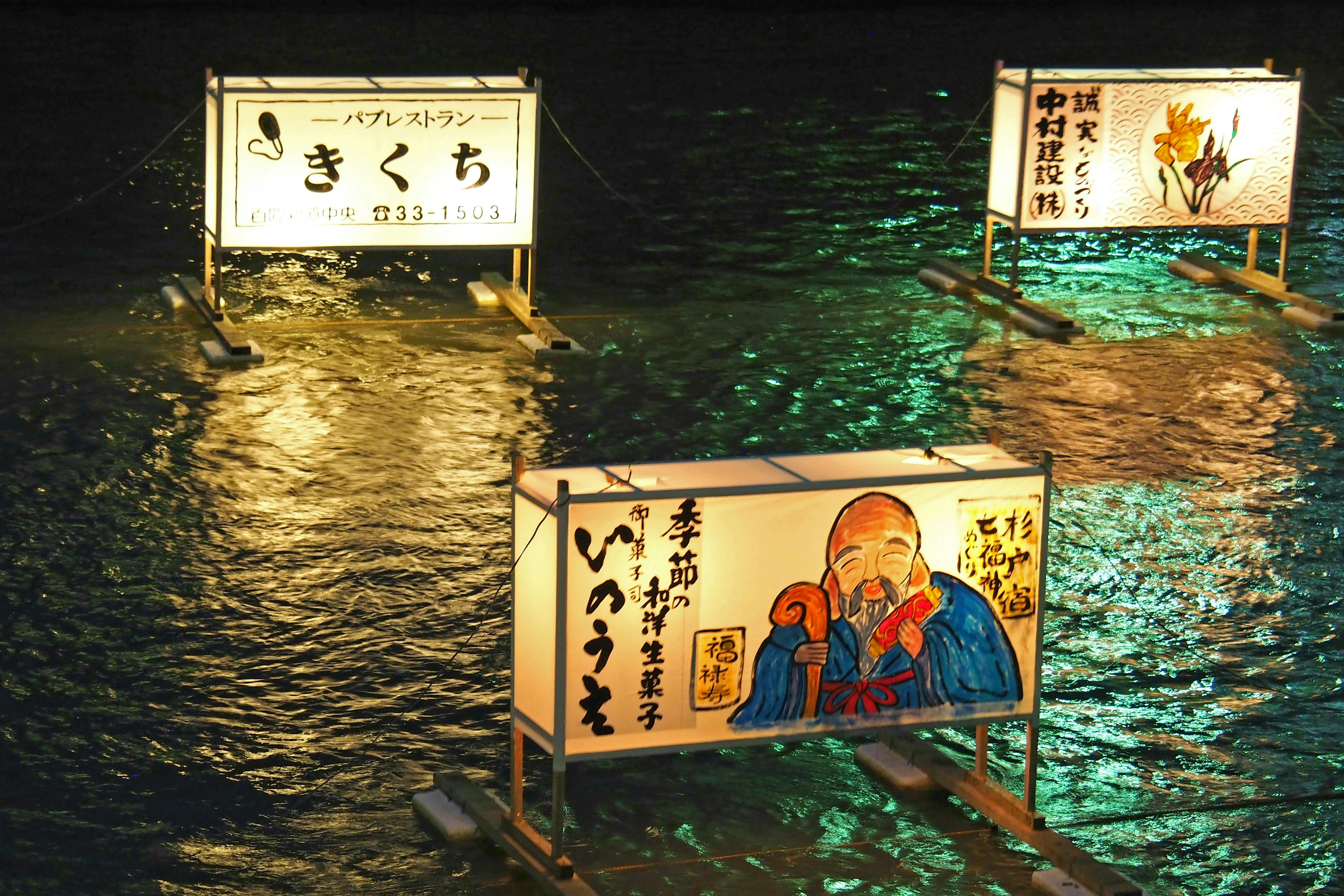 Cartelli illuminati che galleggiano sull'acqua di notte