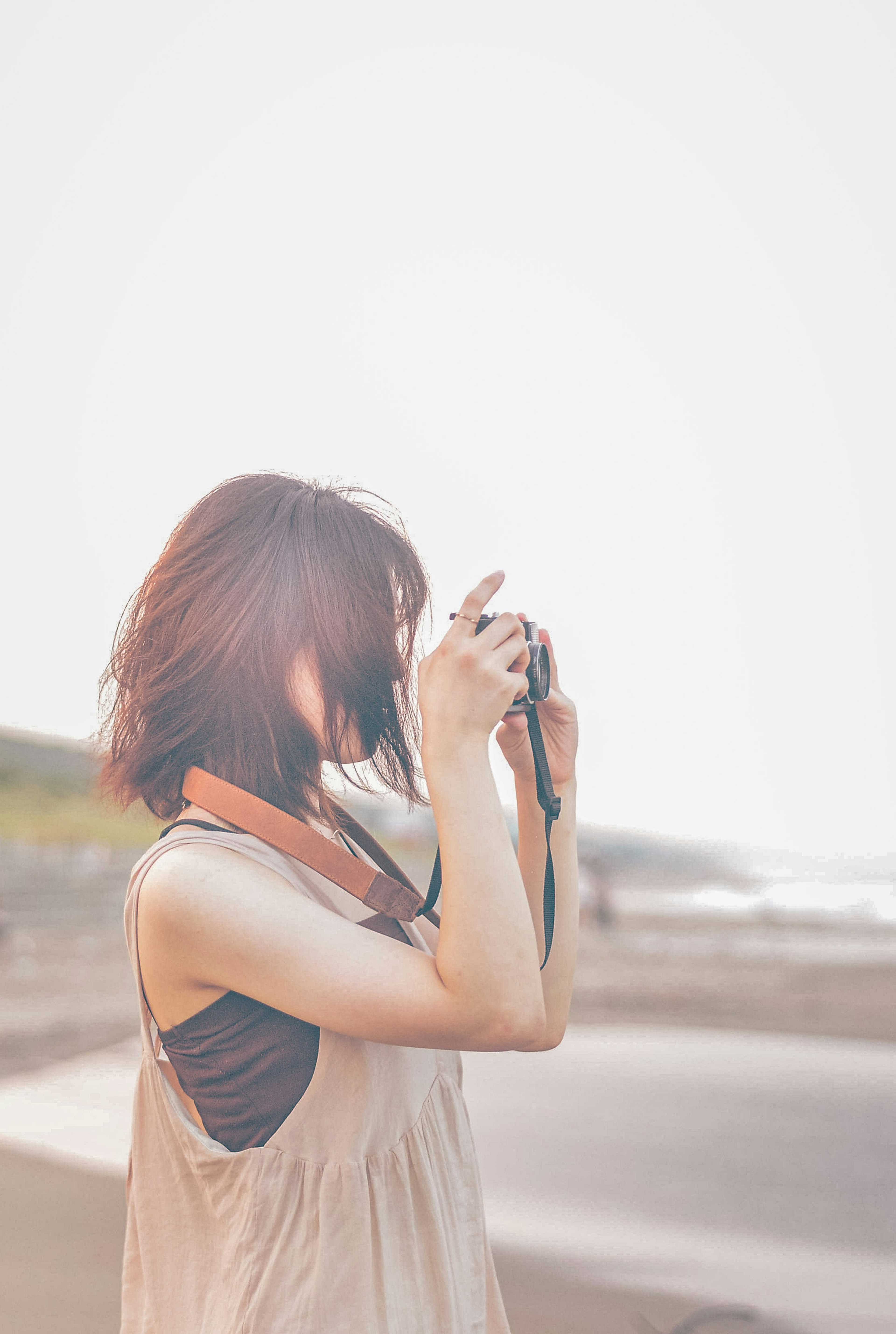 Frau, die am Strand mit einer Kamera Fotos macht