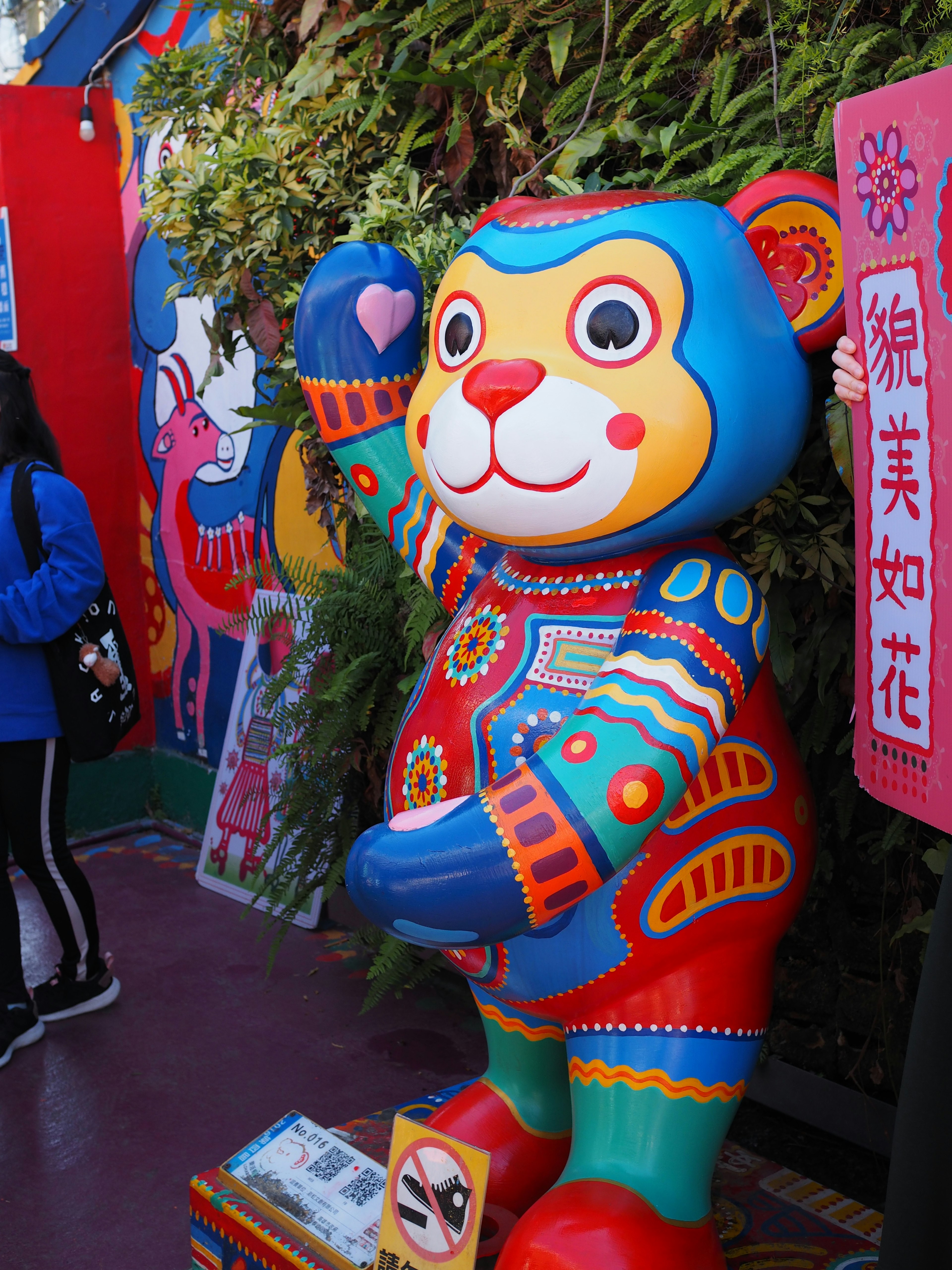 Statue d'ours colorée agitant la main avec une fresque murale vibrante en arrière-plan