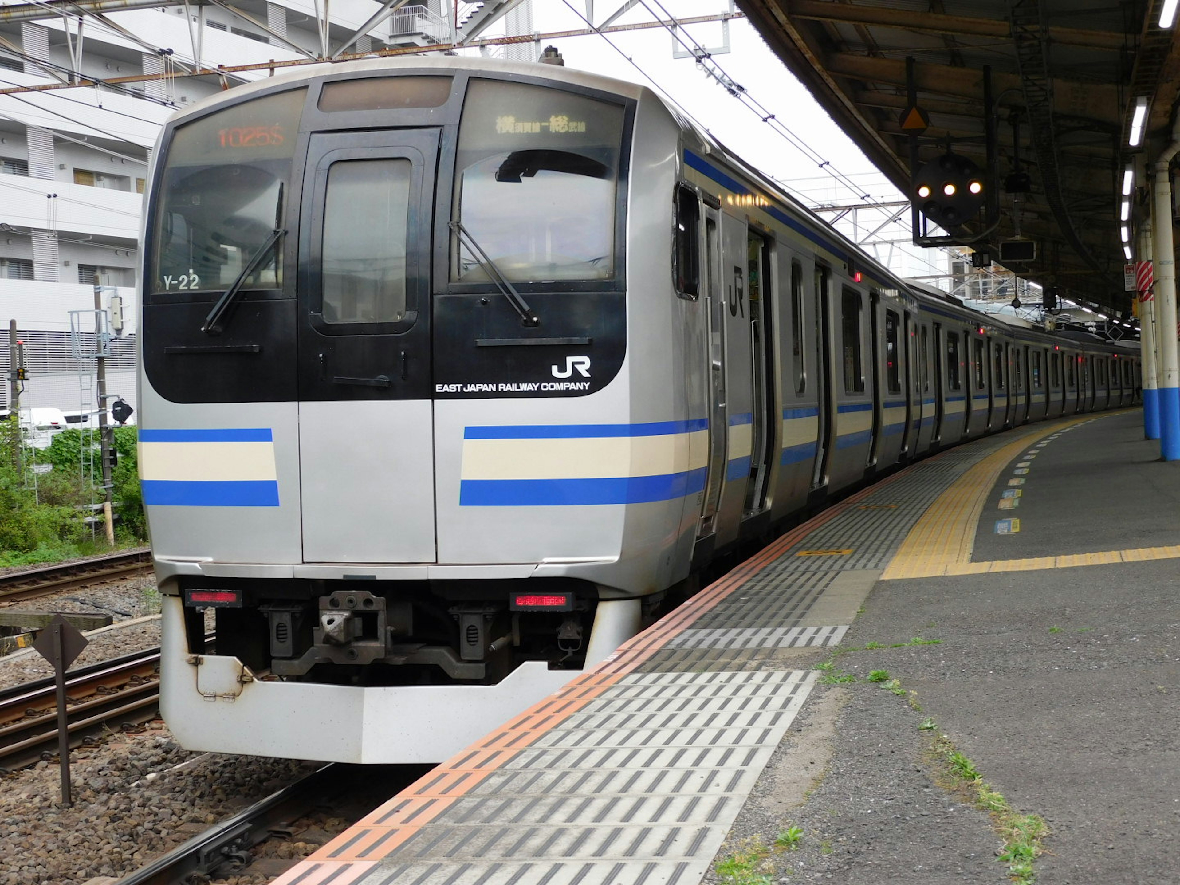 青いストライプのある日本の電車が駅に停車中