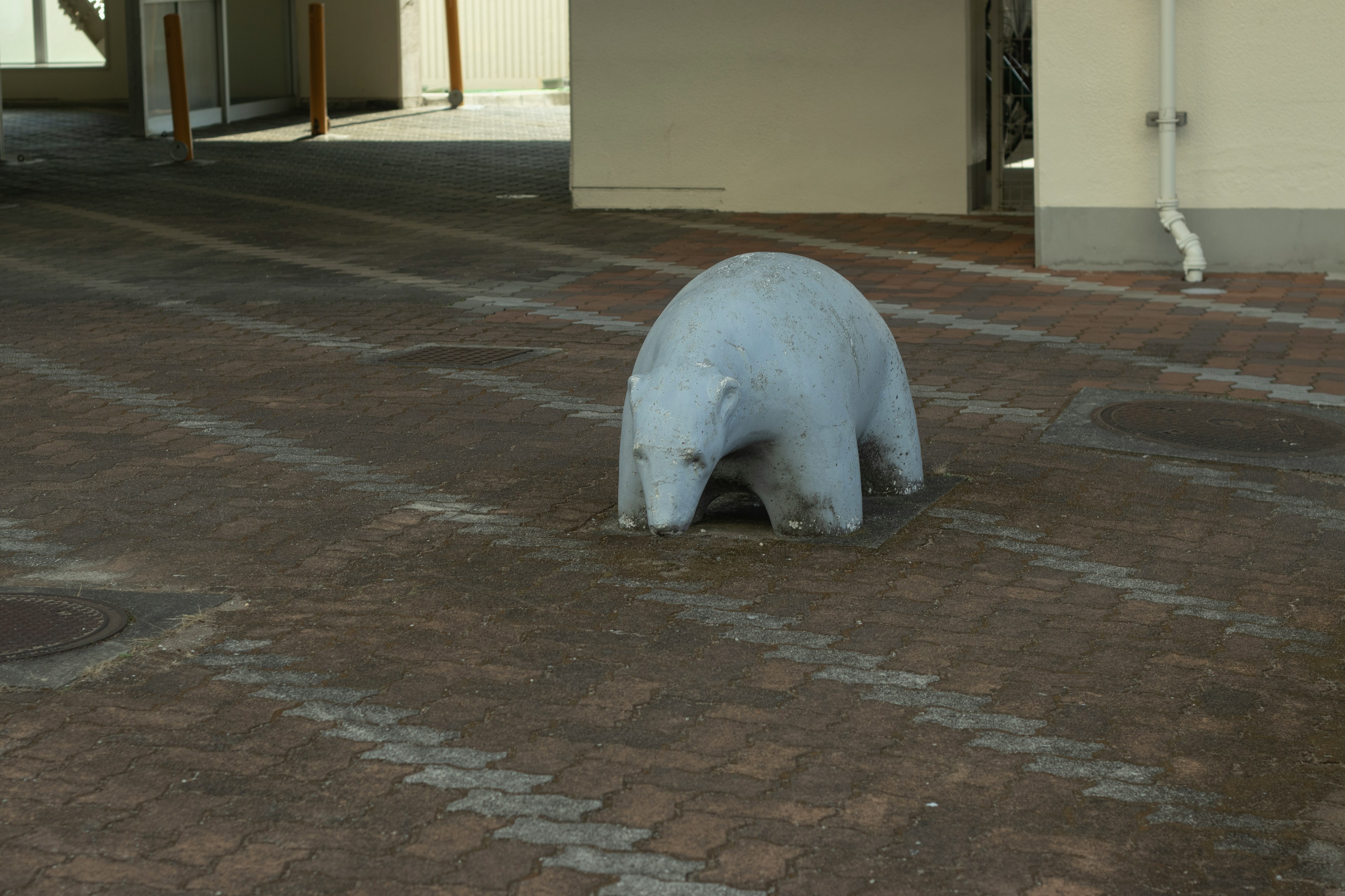 白いクマの彫刻が舗装された地面に座っている