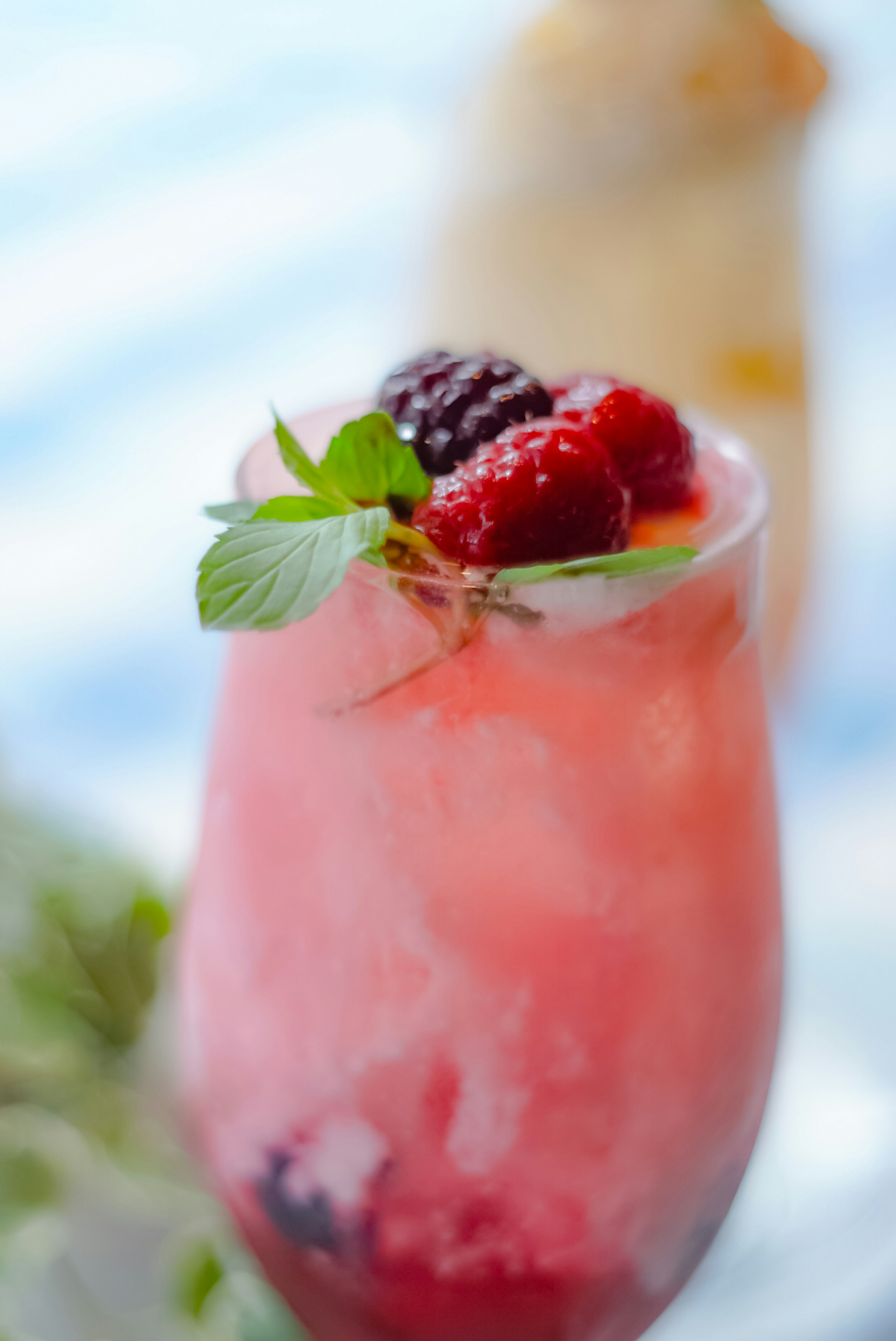 Pink cocktail topped with fresh berries and mint